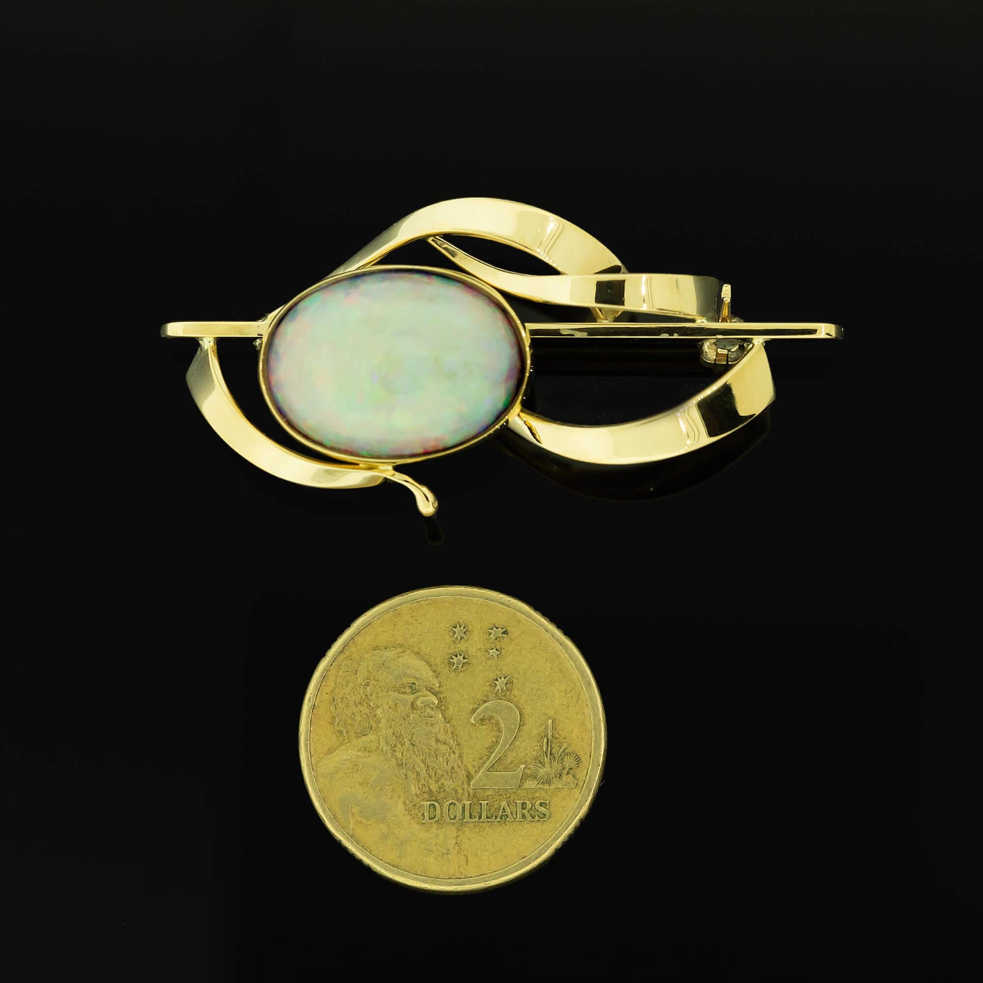 Gold bar brooch with a Coober Pedy solid light opaque opal. The opal is bezel set with curved flat twisting ribbons with a gold pin & roller catch completing the brooch.

Gemstone: Opal, solid light opaque Coober Pedy opal, cabochon cut with a light