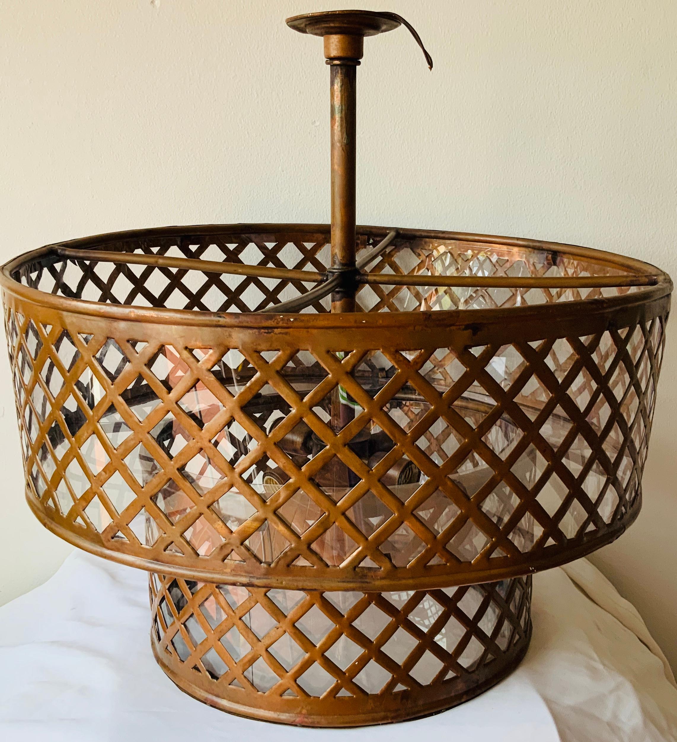This is a double wide cylinders shaped basket copper lamp. There is one small one in the bottom and a large one in the upper part. A copper mesh adorns both cylinders. In the center, a large wide strong copper hollow stem (carry the electrical wire)