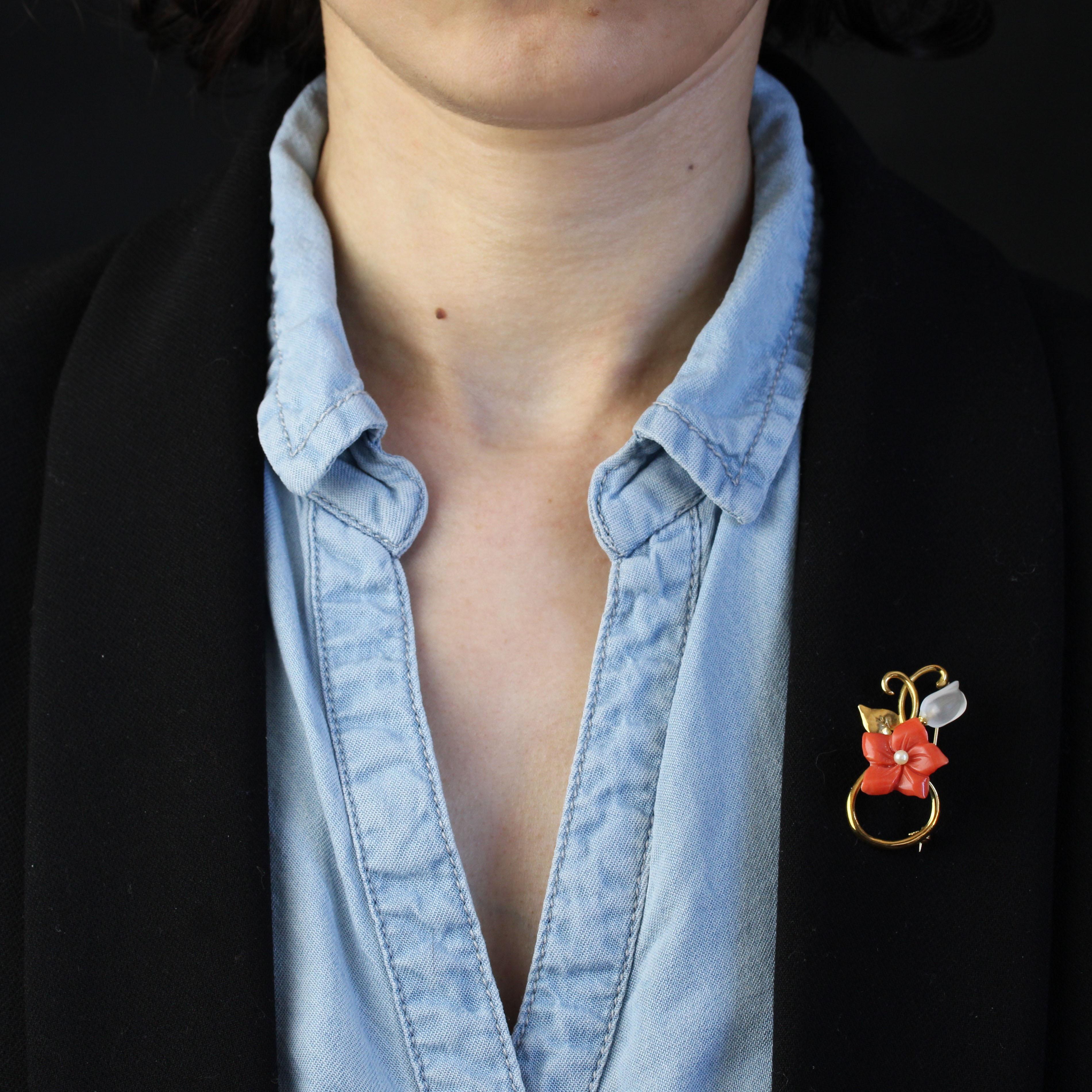 Broche en or jaune 18 carats, poinçon tête d'aigle.
Cette broche d'occasion en or jaune est entrelacée de fils d'or et décorée d'une fleur taillée dans du corail avec une petite perle de culture en son centre. La fleur est accompagnée de deux