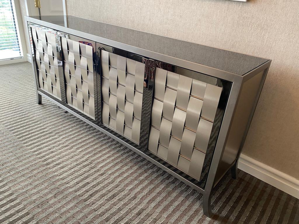 This steel and metal credenza by Ello has woven steel front design and black glass top having 4 front doors Glass shelving to the inside steel panels to the sides. Note the splayed feet design.
Well-made and in wonderful condition! By Ello.
 