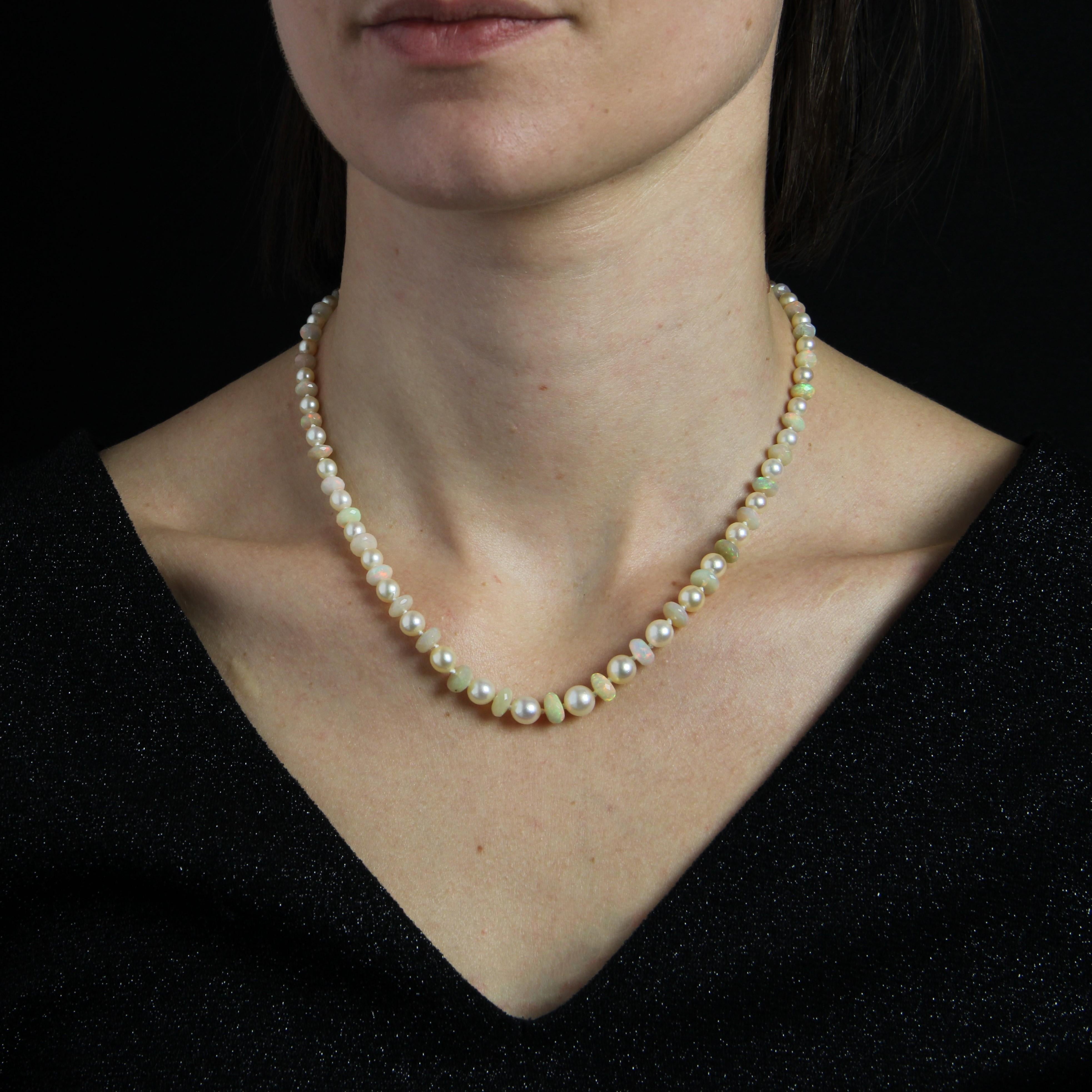 Baume Creation.
Necklace of pearly white oriental cultured pearls, separated by flat, faceted opal beads. The clasp is in 18 Karat white gold, eagle-head hallmark, ratchet with safety chain. It is rectangular with cut sides and set with rose-cut