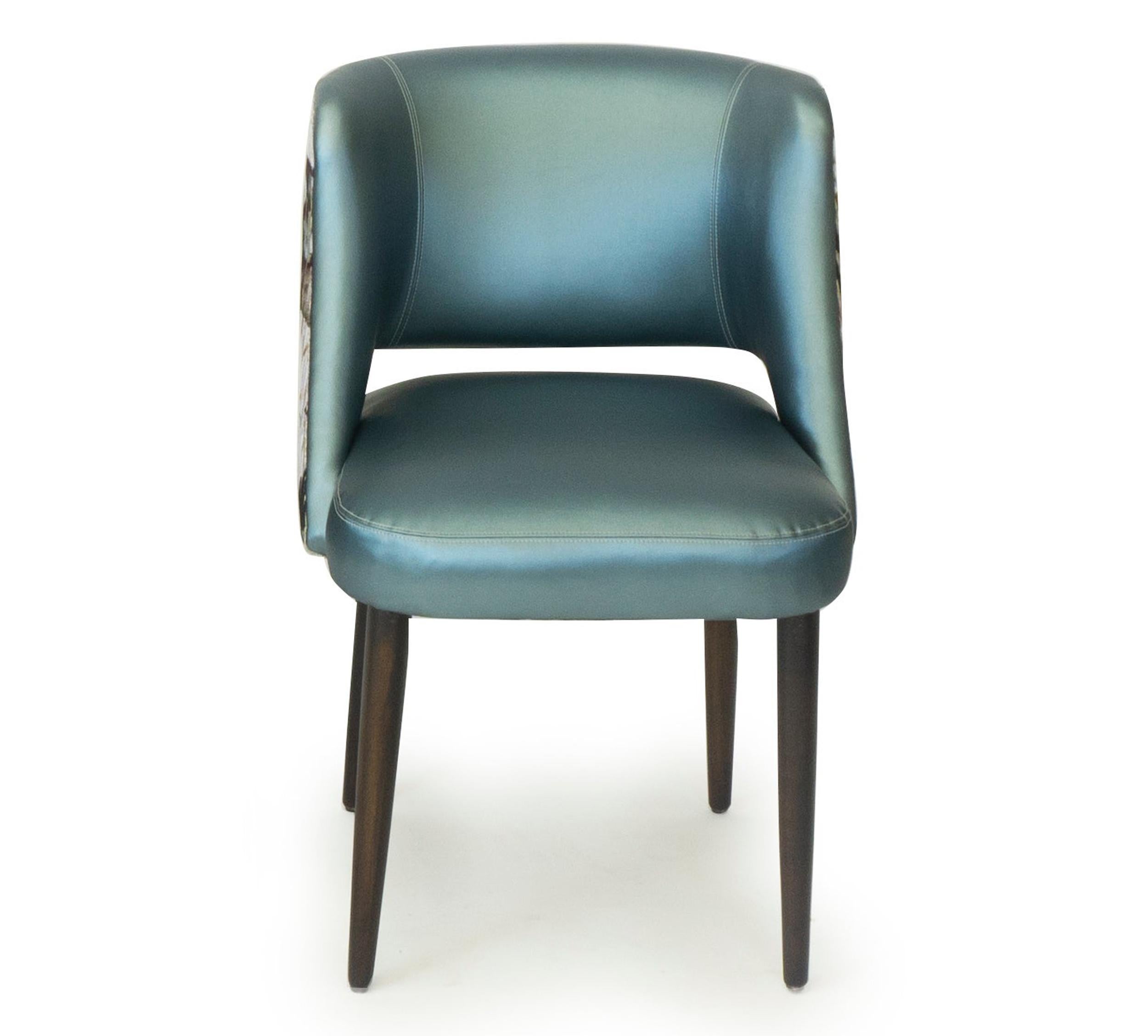 Moderner Esszimmerstuhl mit entspannt geschwungener Rückenlehne. Abgebildet in einer Kombination aus blauem Vinyl und einem floralen Jacquard-Samt von Romo Fabrics. Beine aus Walnussholz. Dieser Stuhl ist vollständig anpassbar und kann wie