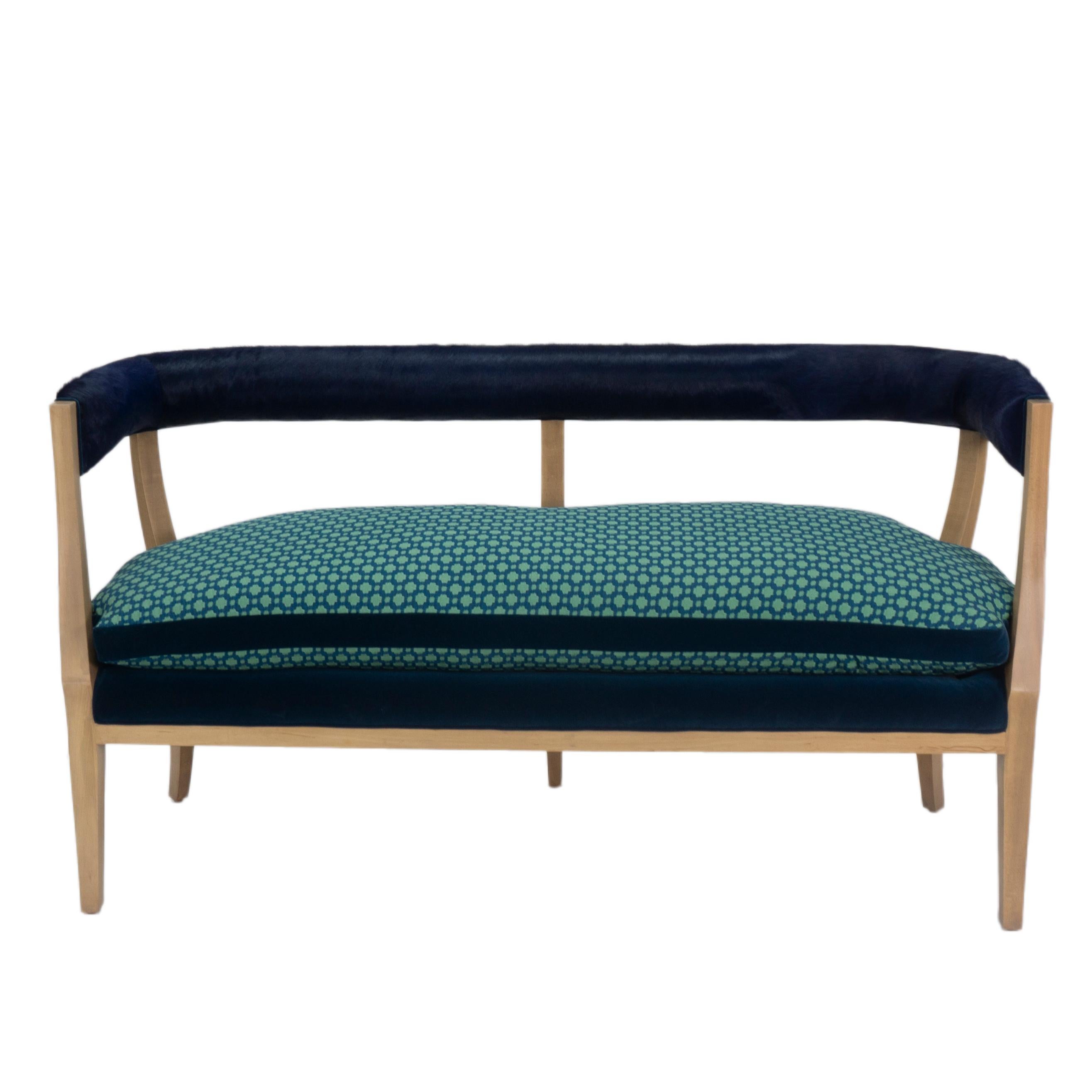 Modern classic curved back dining bench upholstered with blue velvet decking and geometric patterned loose cushion. The back features a blue dyed cowhide. The bench also features velvet piping on the deck and back. Exposed poplar legs finished and