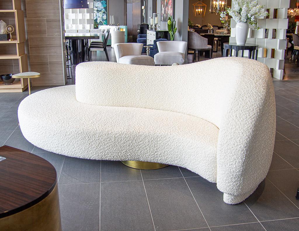 This modern curved Italian boudoir cloud sofa will take your living space to another level with its unique curved shape and brass metal supports. Upholstered in a beautiful textured off white fabric, this sofa is the perfect combination of modern