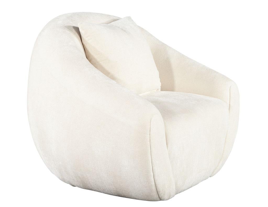 Modern curved linen swivel chair by Ellen Degeneres Wicma Chair. Sophisticated curved design with clean lines. Features swivel mechanism for optimal lounging space. Upholstered in a luxurious off-white fabric. Accent pillow included. Matching sofa