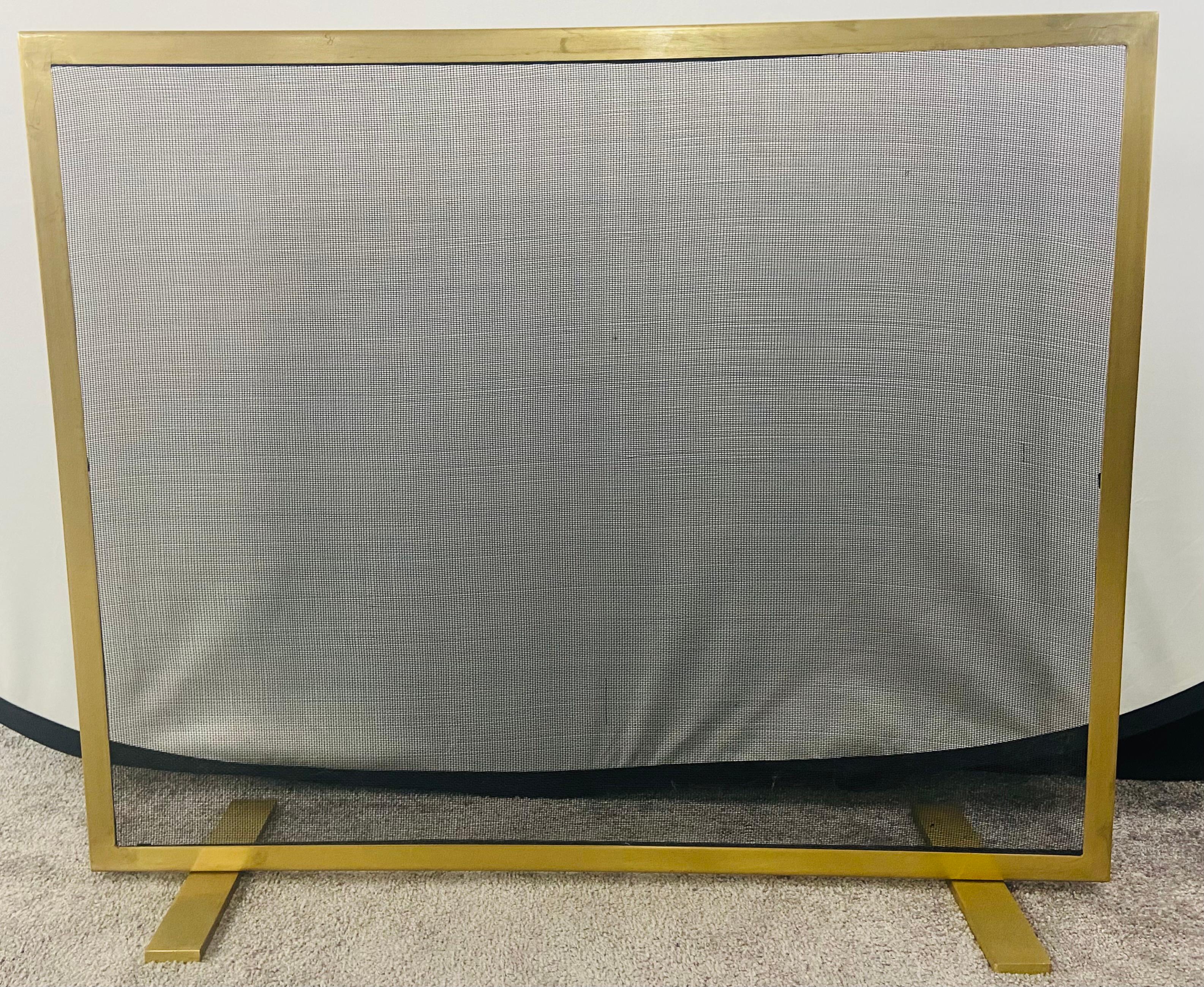 A stylish Modern custom made fire screen featuring a rectangular shape and hand-carved of high quality brass and black iron mesh. The screen is elevated by rectangular brass feet, all in the same color. Elegant and simplistic, this modernist fire