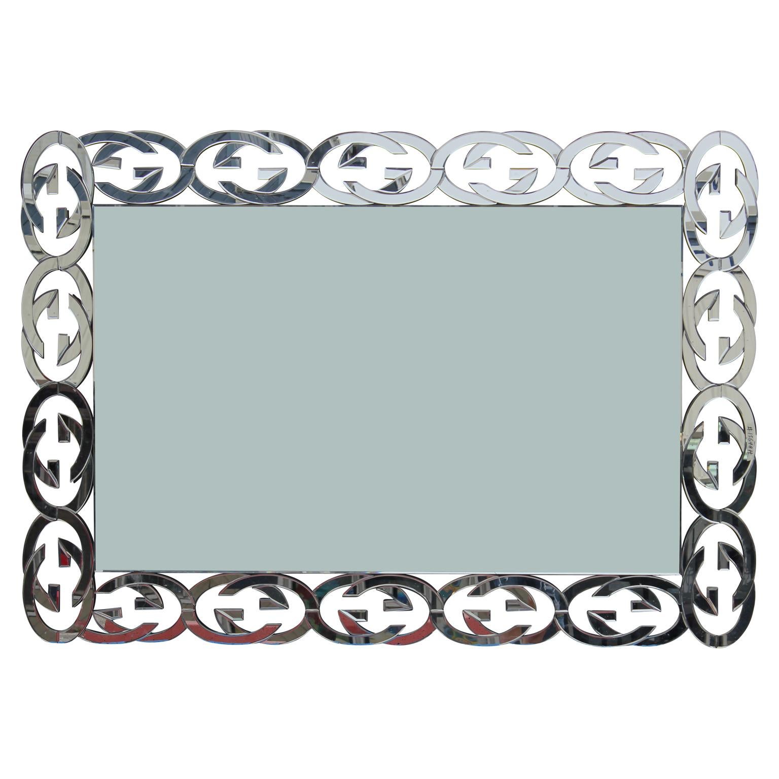 Stunning modern custom chrome wall or mantel mirror inspired by Gucci with a series of the Classic Gucci 'GG' symbol all the way around the frame. The center mirror is cracked (pictured) but everything else is in perfect condition.