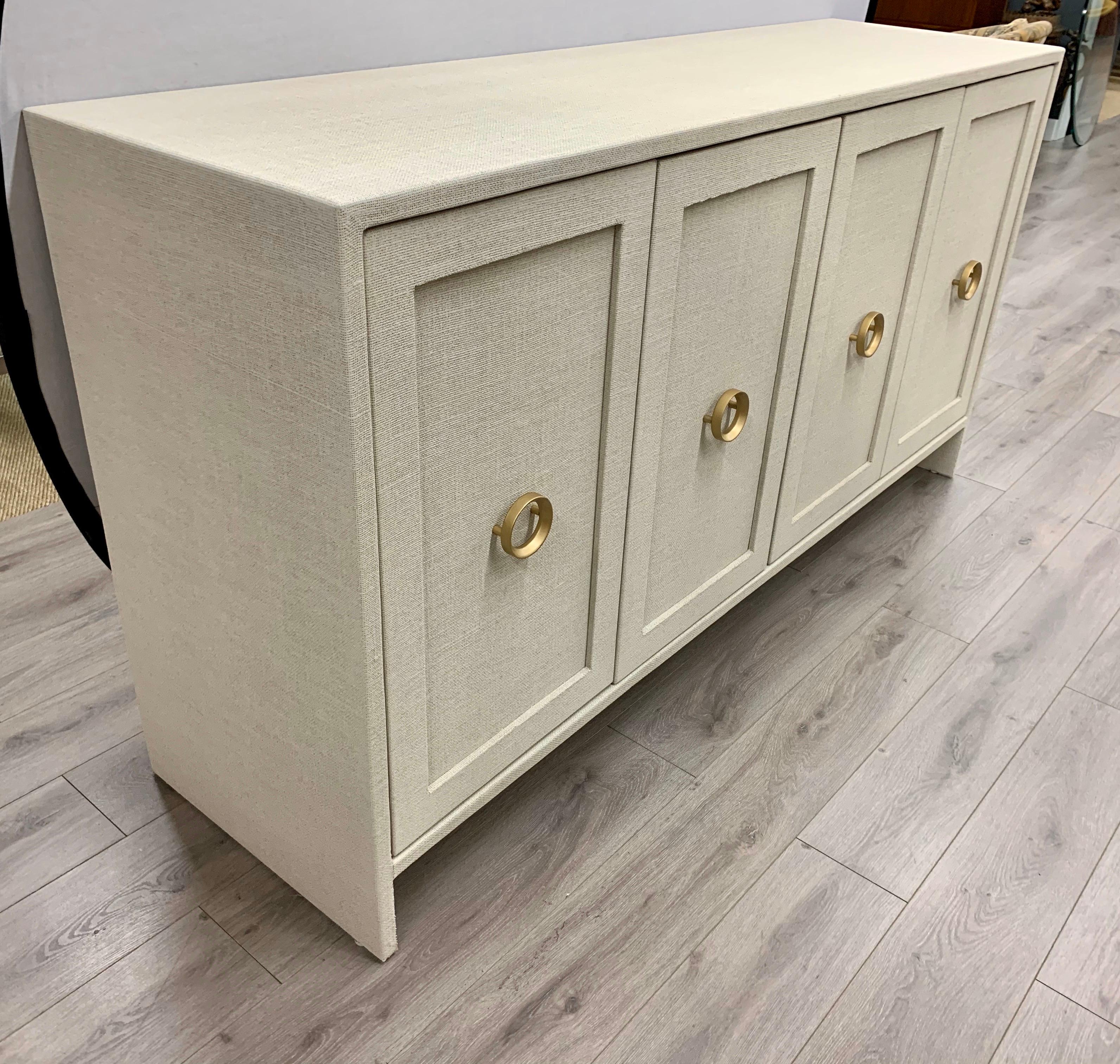 Sleek, simple lines give this credenza a Mid-Century Modern feel and is wrapped by hand in fine linen then given a multi-layered paint glaze. It has two pairs of double doors that open to shelving. Round brass handles give it a decorative flair. A