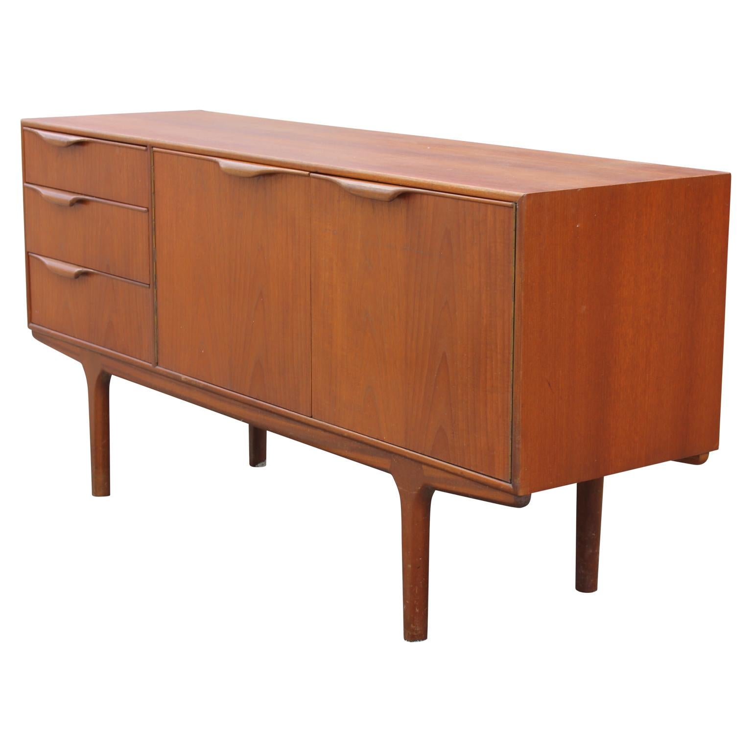 Modern teak credenza designed by Tom Roberston for McIntosh. The piece has three drawers for storage space. In the top drawer, it is lined with red velvet and have a silverware tray. The two swing-out drawers reveal two shelves with the top being an