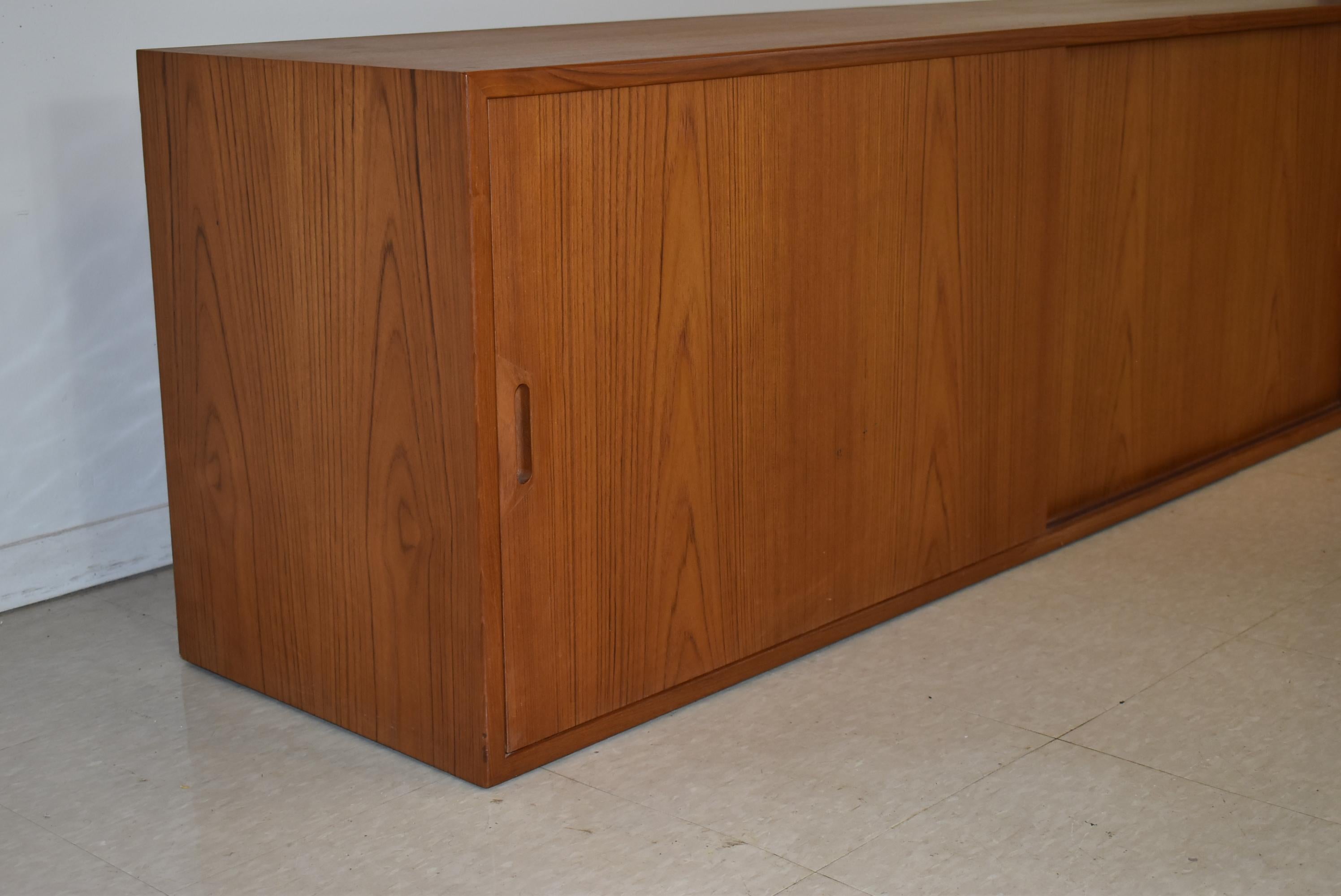 Modern Danish oiled teak floating wall cabinet with two sliding doors and removable shelves. No mounting hardware.