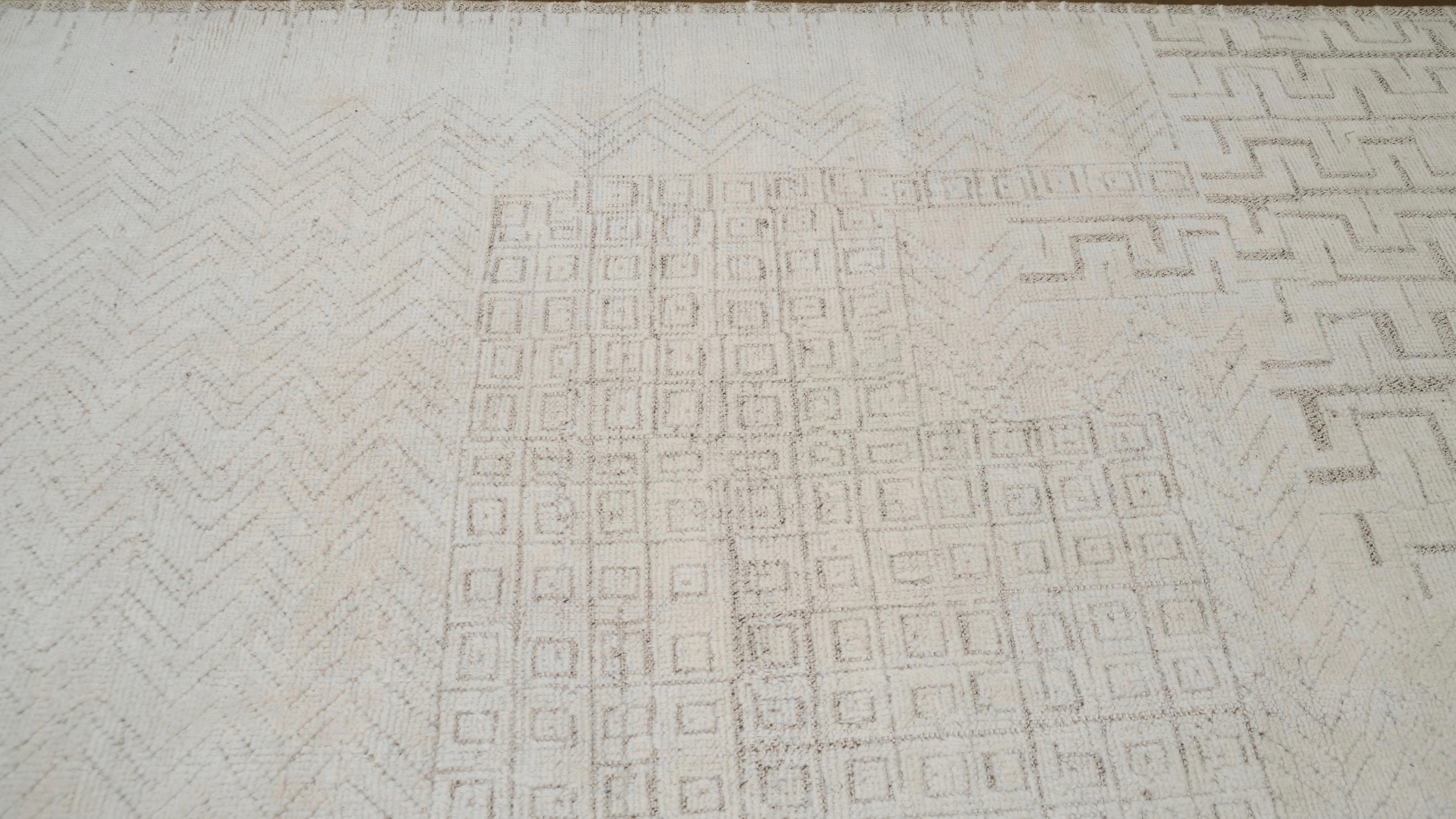 Doté d'un design abstrait raffiné avec des motifs géométriques délicatement tissés sur un fond doux et neutre, ce tapis allie sophistication moderne et savoir-faire artisanal. Les motifs délicats émergent comme un jeu de tons, offrant une texture et