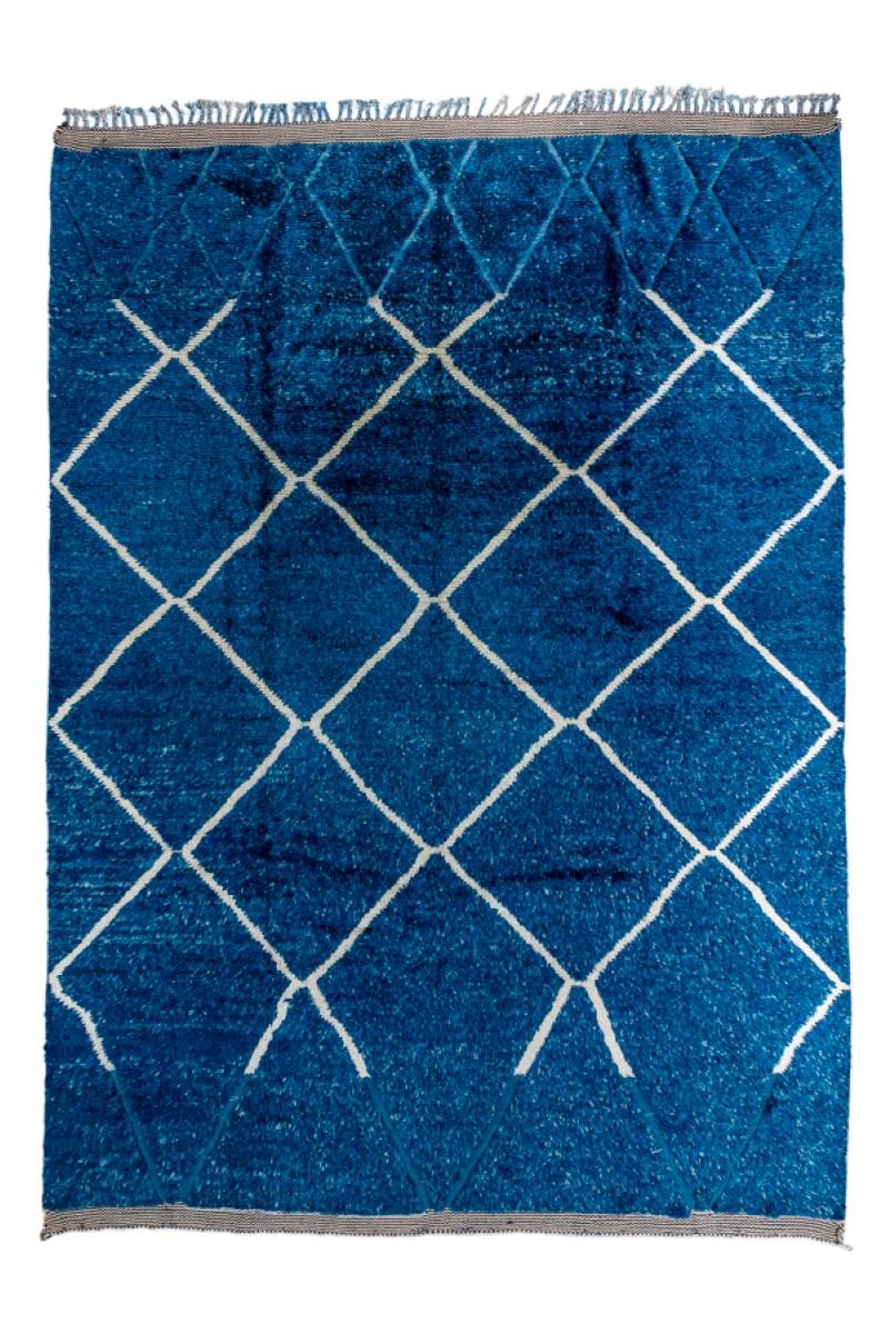 The somewhat irregular ecru diamond trellis breaks toward each end of the denim blue field and continues as a lighter blue tone-on-tone effect. The lattice is open at both ecru ends. At one end is a plainweave finish followed by braided tassels.