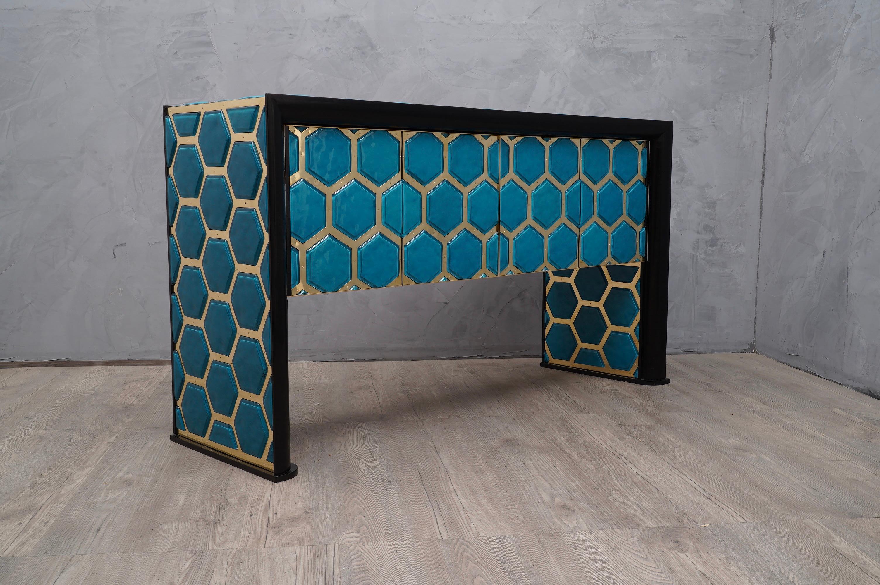 Amazing sideboards in an incredible design, also due to the use of very special and precious materials, Murano glass and brass.

The structure of the sideboard is in wood, with a frame along the front in black lacquer. The top and sides are covered