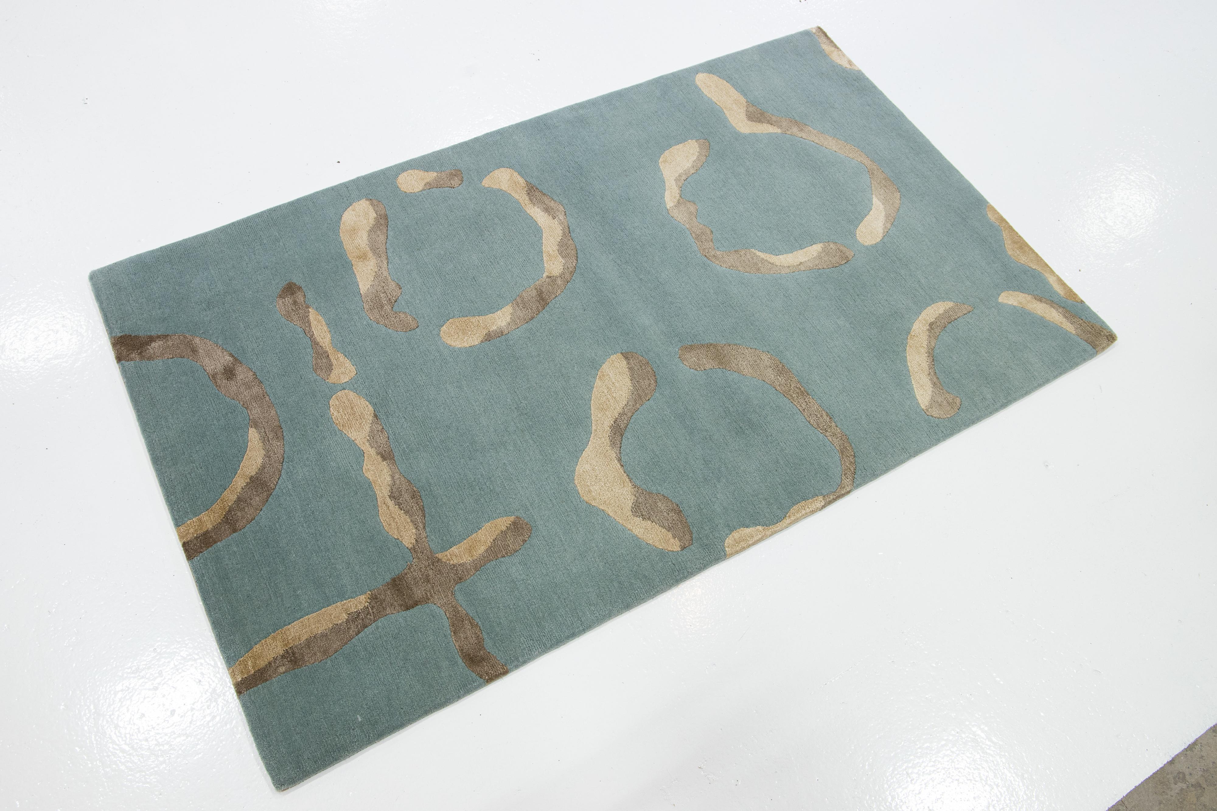 This modern Custom rug features Elegant hieroglyphics courtesy of world-famous designer Kevin Walz. It is a contemporary, symbolic rug rendered in chic colorways, fine Himalayan wool, and silk—stunning blues with hints of silver throughout the