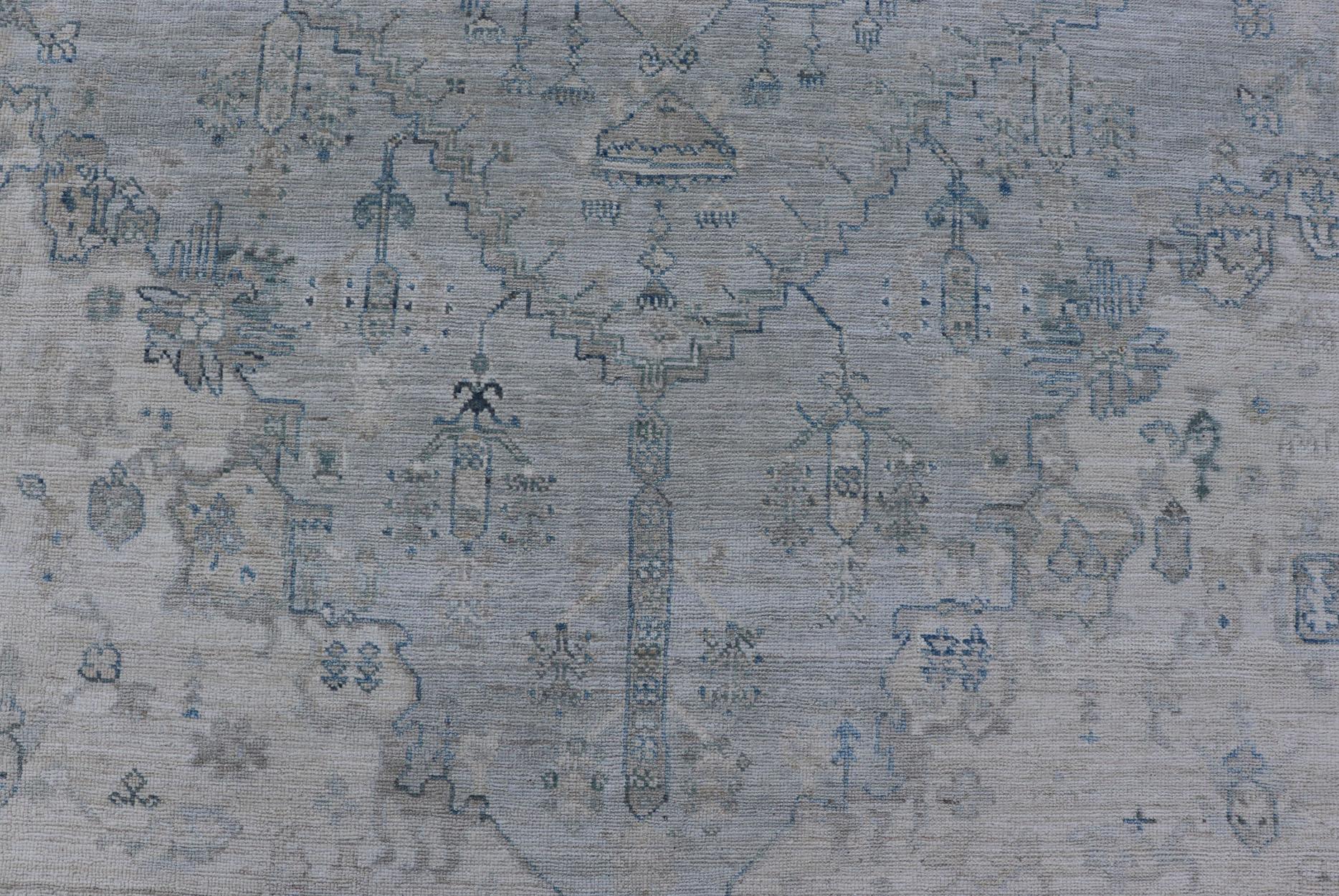 Moderner, entworfener Teppich mit hellblauem Hintergrund und Stammesmedaillon-Motiven (Wolle) im Angebot