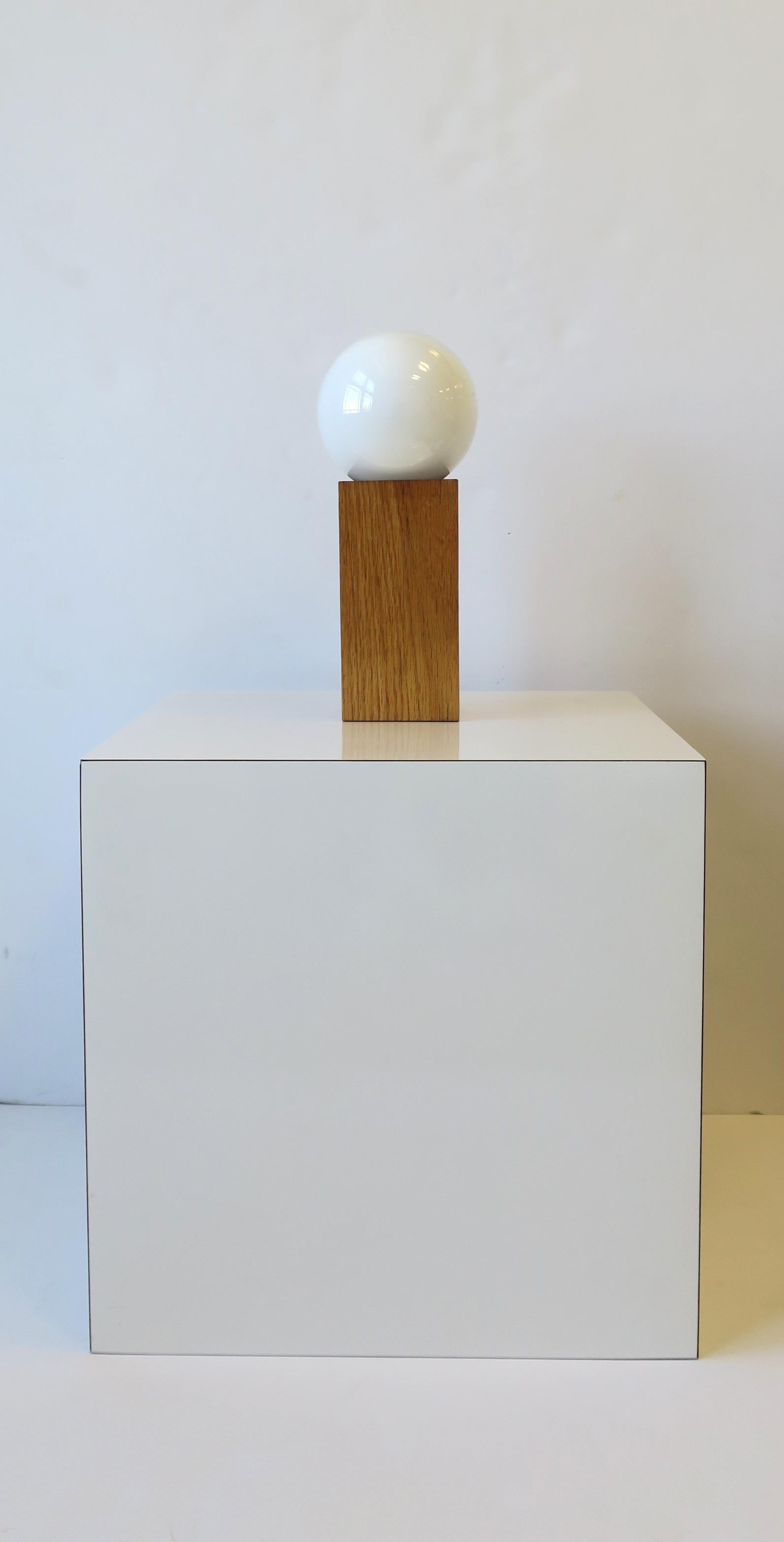 A '70s Modern or Postmodern period wood desk or table lamp with white globe-like lamp/bulb, circa late-20th century, 1970s, USA. In fine working order. On/Off switch on cord a shown. 

Dimensions: 4.25