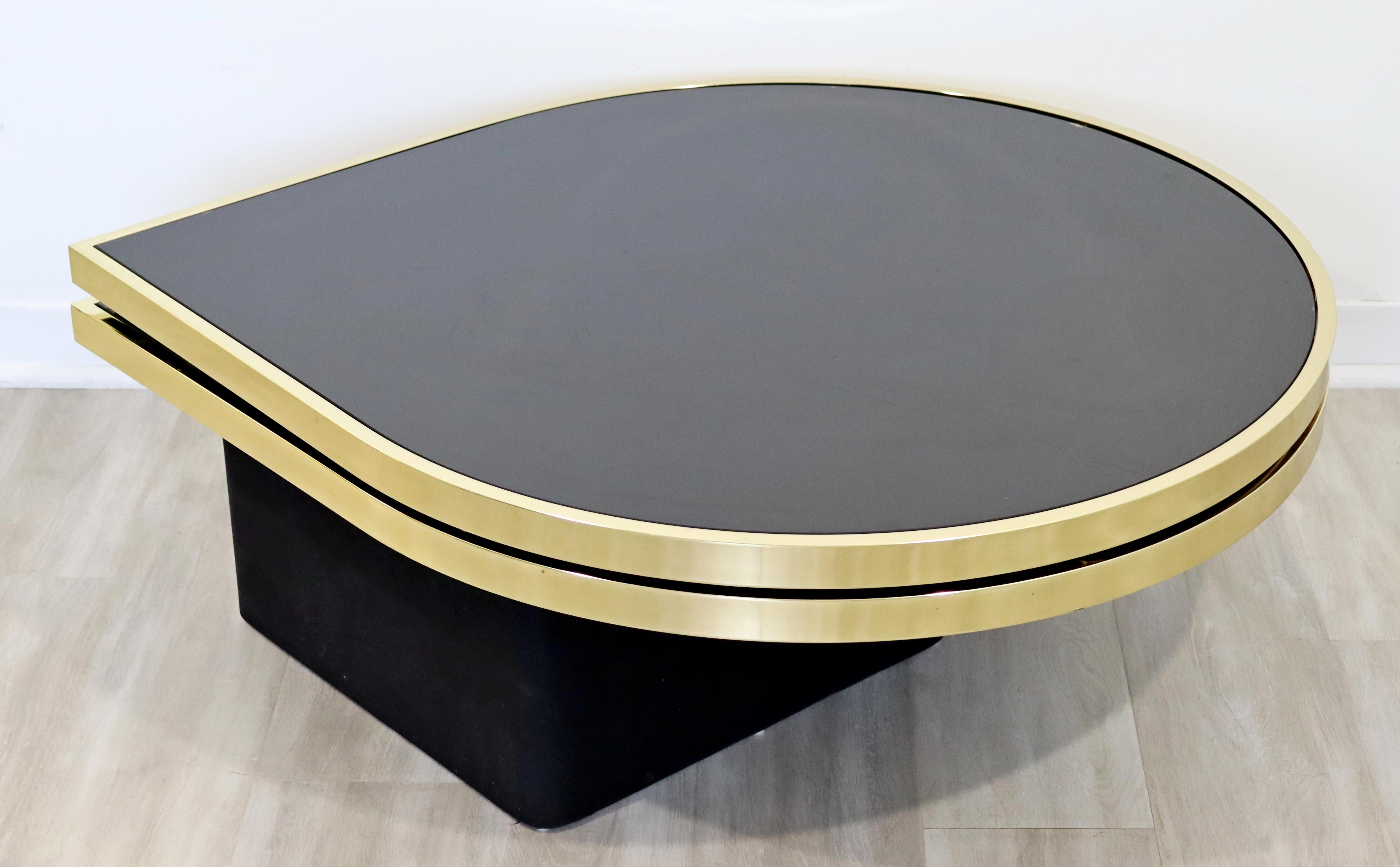 For your consideration is a terrific, teardrop shaped, brass coffee or cocktail table, with two swiveling tiers and smoked glass tops, by the Design Institute of America, circa the 1980s. In excellent vintage condition. The dimensions are 43