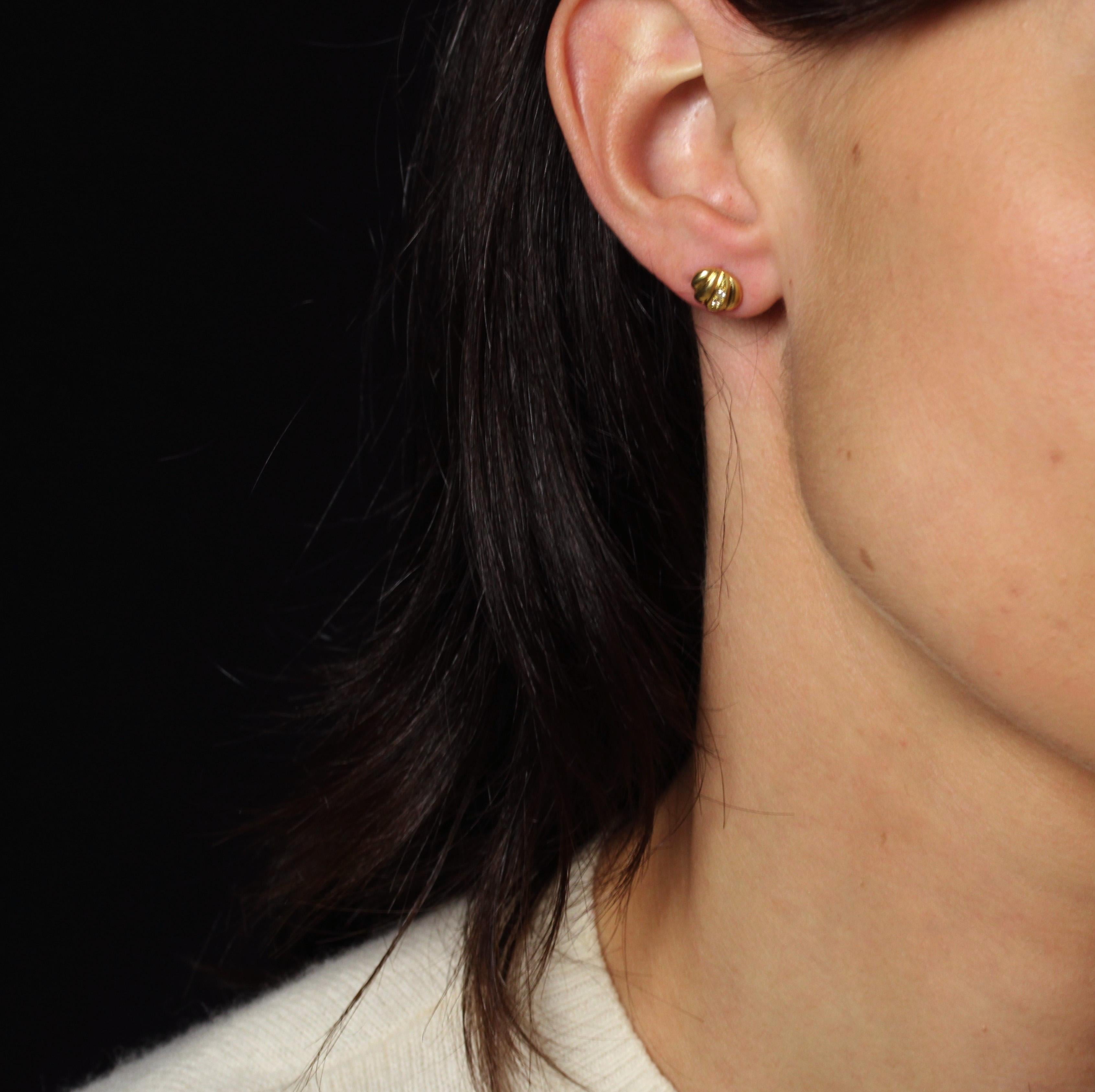 For pierced ears.
Earrings in 18 karat yellow gold, eagle head hallmark.
Earrings in yellow gold, slightly domed and gadrooned, adorned with 2 small diamonds on a gadroon. The clasp is a butterfly.
Height : 6.8 mm approximately, width : 8.3 mm
