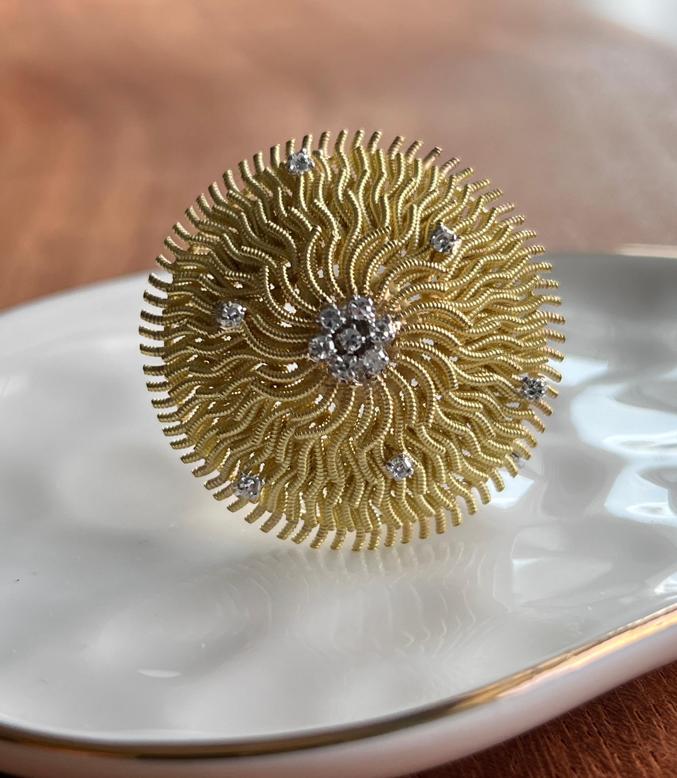 Diese bezaubernde Brosche mit Wirbel aus den 1960/70er Jahren zeigt die kühne künstlerische Vision, die das Schmuckdesign der Mitte des Jahrhunderts bestimmte. Das aus 18-karätigem Gelb- und Weißgold gefertigte Schmuckstück weist ein kompliziertes,