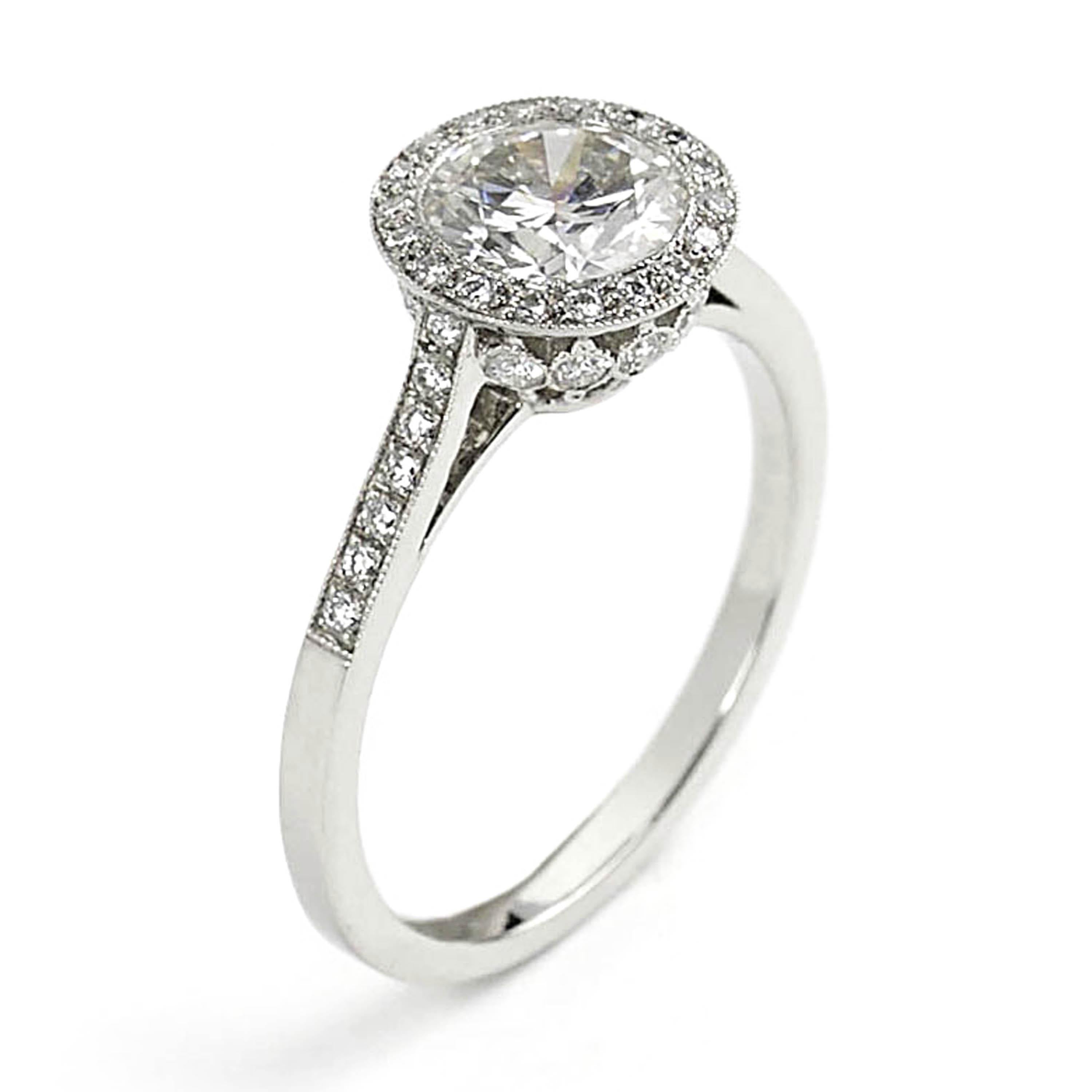 A modern solitaire diamond halo design ring, set with an approximately 1.00 carat, H/I colour, VS2/SI1 clarity, round brilliant-cut diamond, with surrounding micro pavé set round brilliant-cut diamonds, forming a halo around the solitaire diamond.