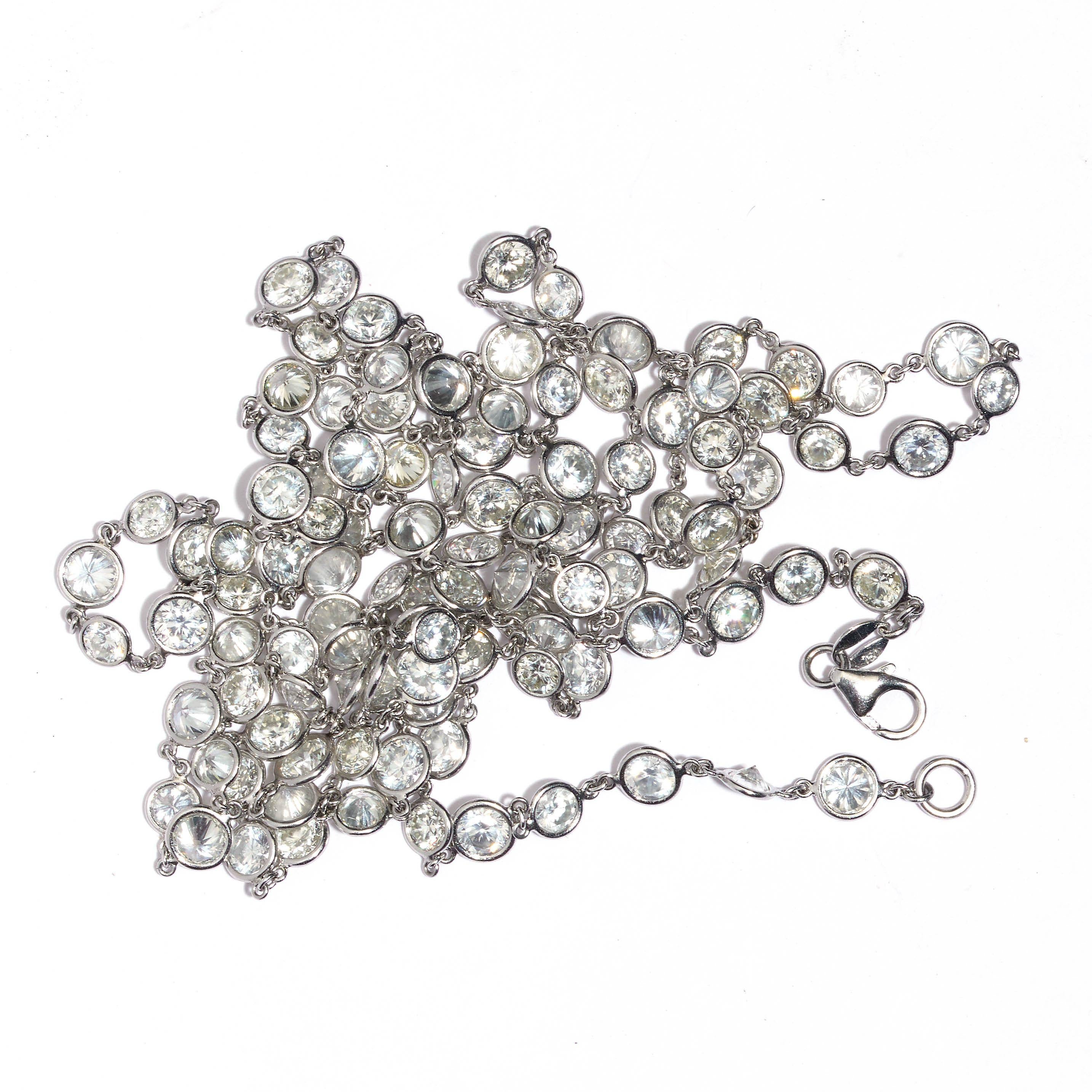 A modern long diamond necklace, comprised of a single row of one hundred and nine round brilliant-cut diamonds, with a given total of 28.09 carats, each diamond in its own spectacle type rub-over setting, mounted in platinum, with a white gold