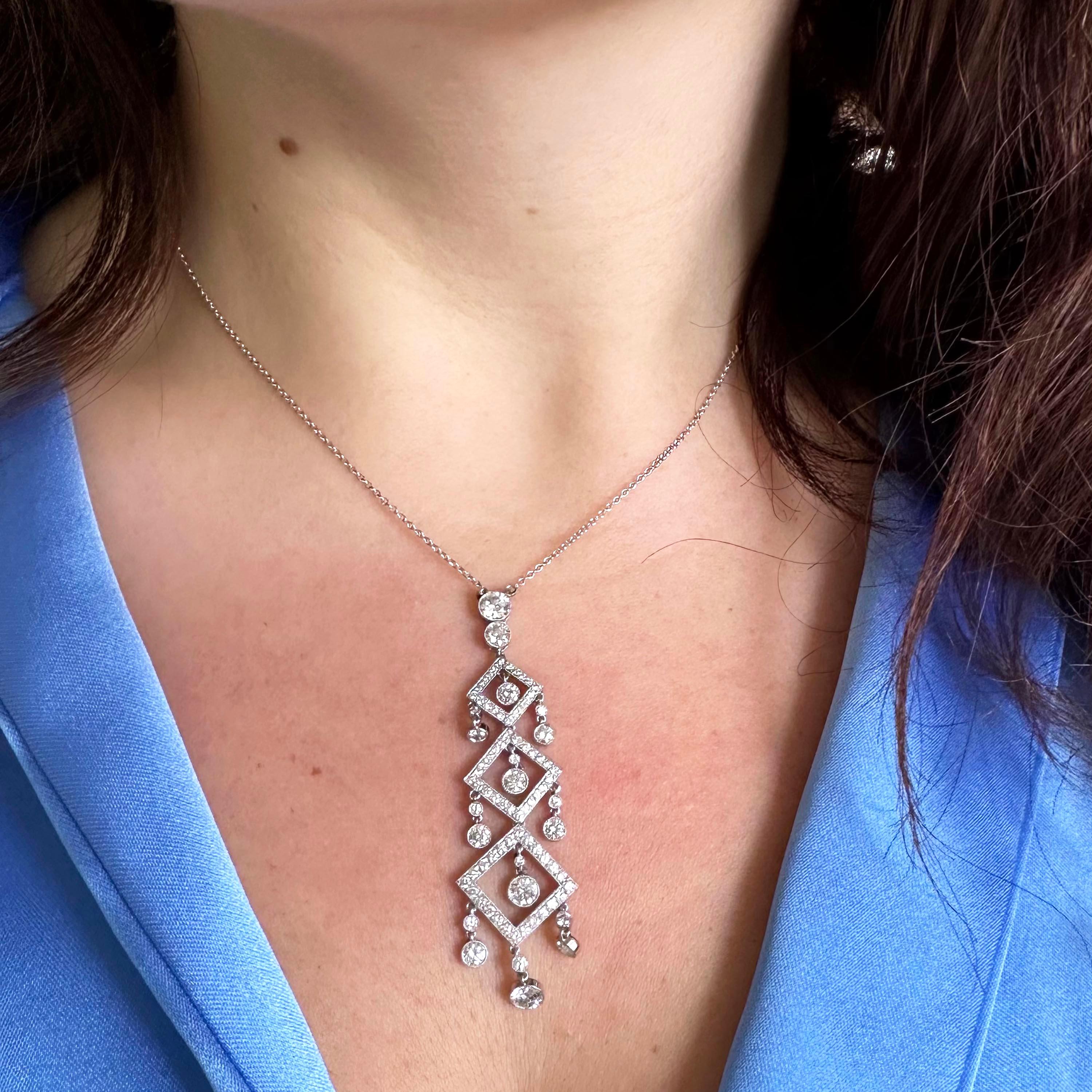 A diamond and platinum pendant, of three graduating open squares, with grain set, round brilliant-cut, diamonds, with two diamonds above and diamond drop pendants in the centre of the squares and suspending from the sides, in rub over settings, with