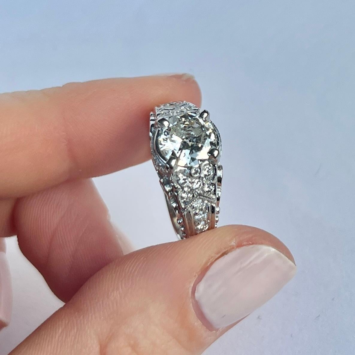 Le diamant central de cette bague mesure environ 1,5ct. Les épaules et la monture contiennent également des diamants plus petits mais très étincelants. Ils totalisent 66 points. La bague est modelée en platine. 

Taille de l'anneau : M ou 6 1/4