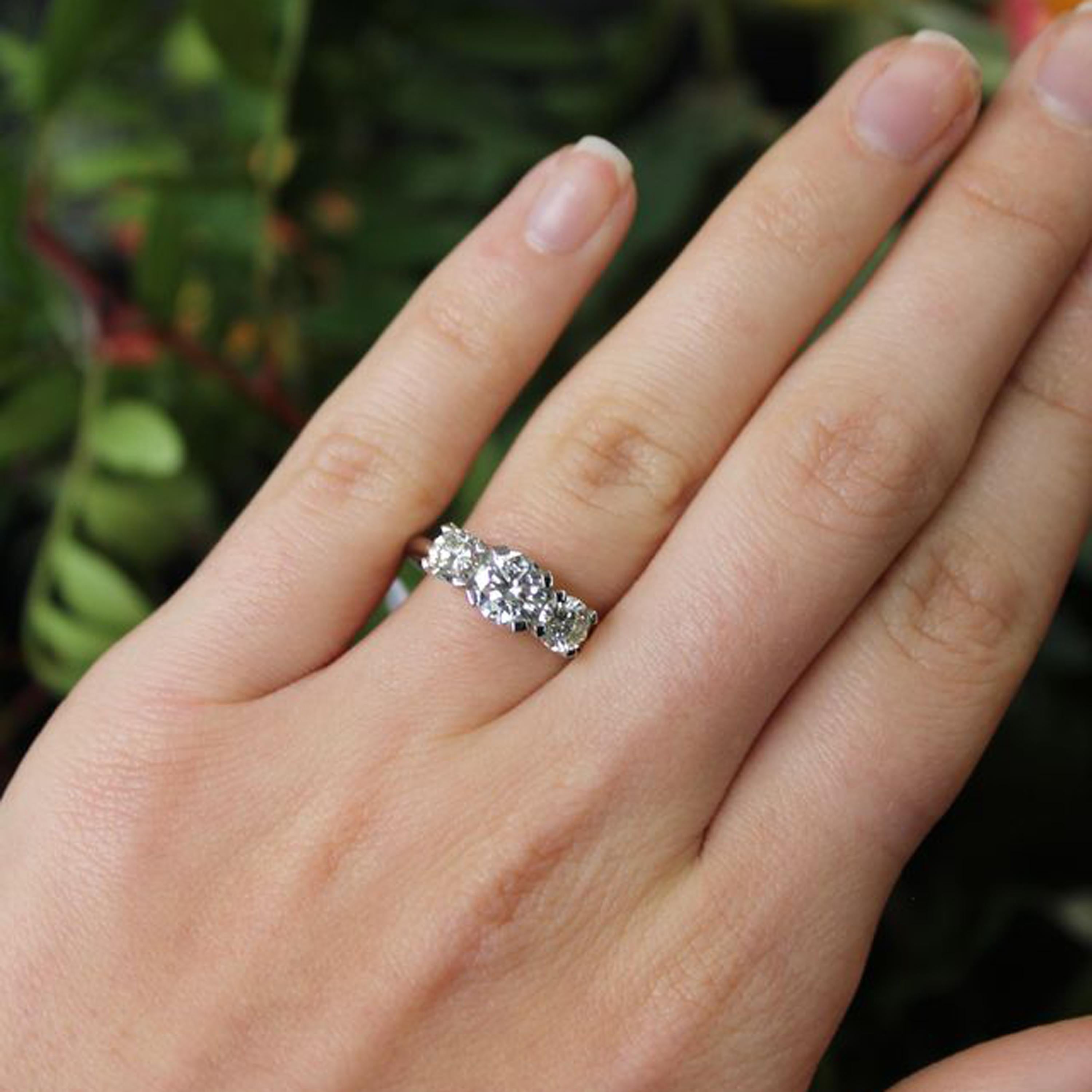 A three stone diamond ring, with a central round brilliant-cut diamond, weighing 0.80 carat, with round brilliant-cut diamonds either side, with an estimated total weight of 0.75 carat, with heavy modern four claw crown settings, onto a tapered
