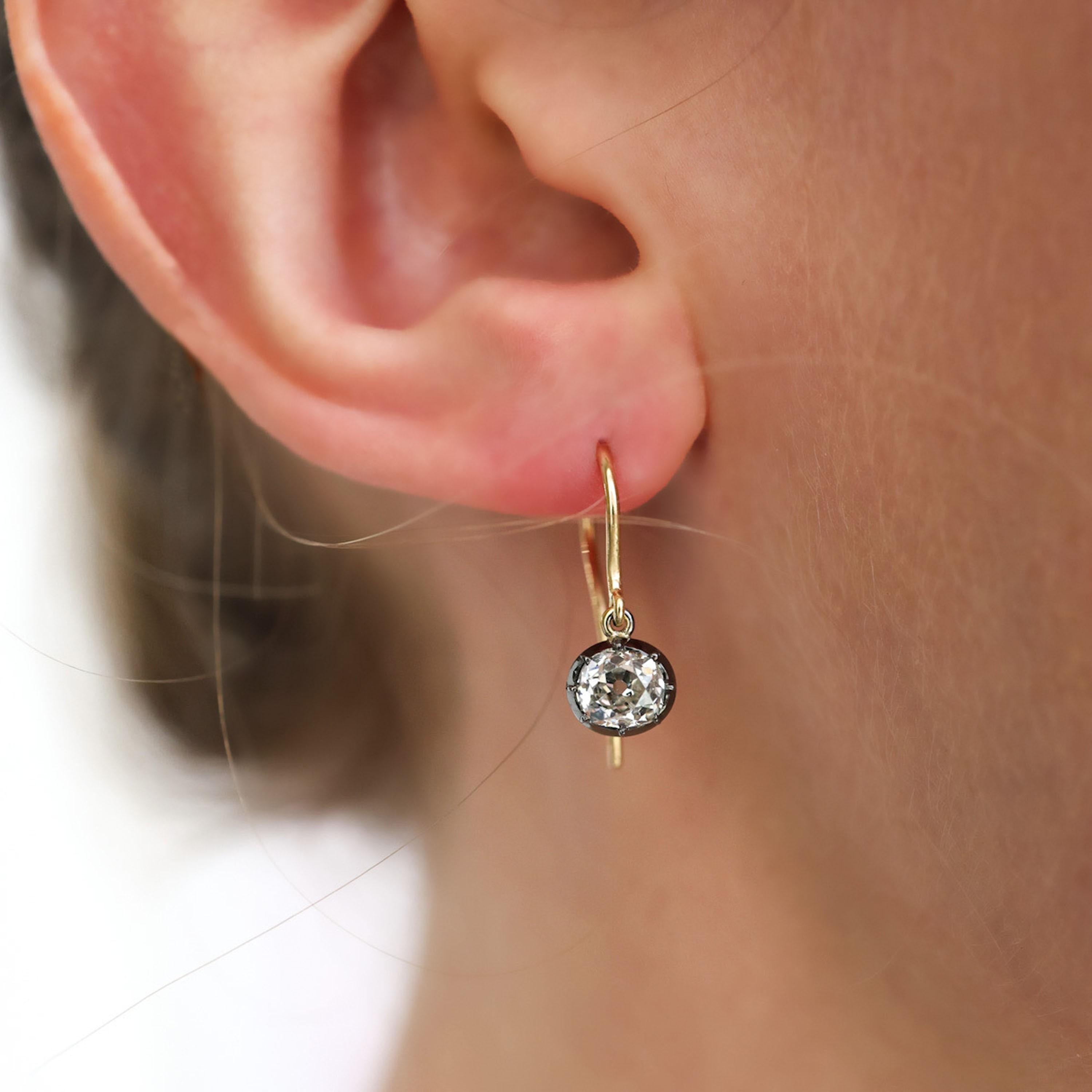 A pair of modern diamond drop earrings, each set with old-cut diamonds, in silver-upon-gold cut down settings, on gold hooks, with a total diamond weight of 1.44 carats. In our opinion the colour is I and our opinion of the clarity is SI1 and SI2.