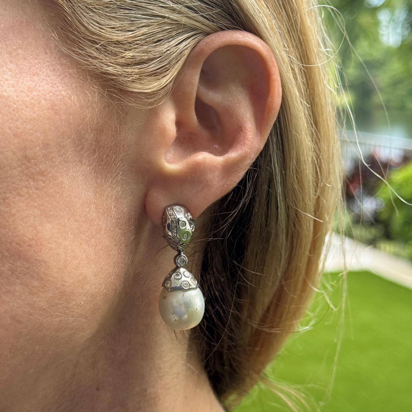 Questi moderni orecchini a goccia di perle barocche con diamante sono realizzati in oro bianco 14 carati e presentano due splendide perle barocche che penzolano elegantemente da incastonature con diamanti. Gli orecchini sono impreziositi da 58