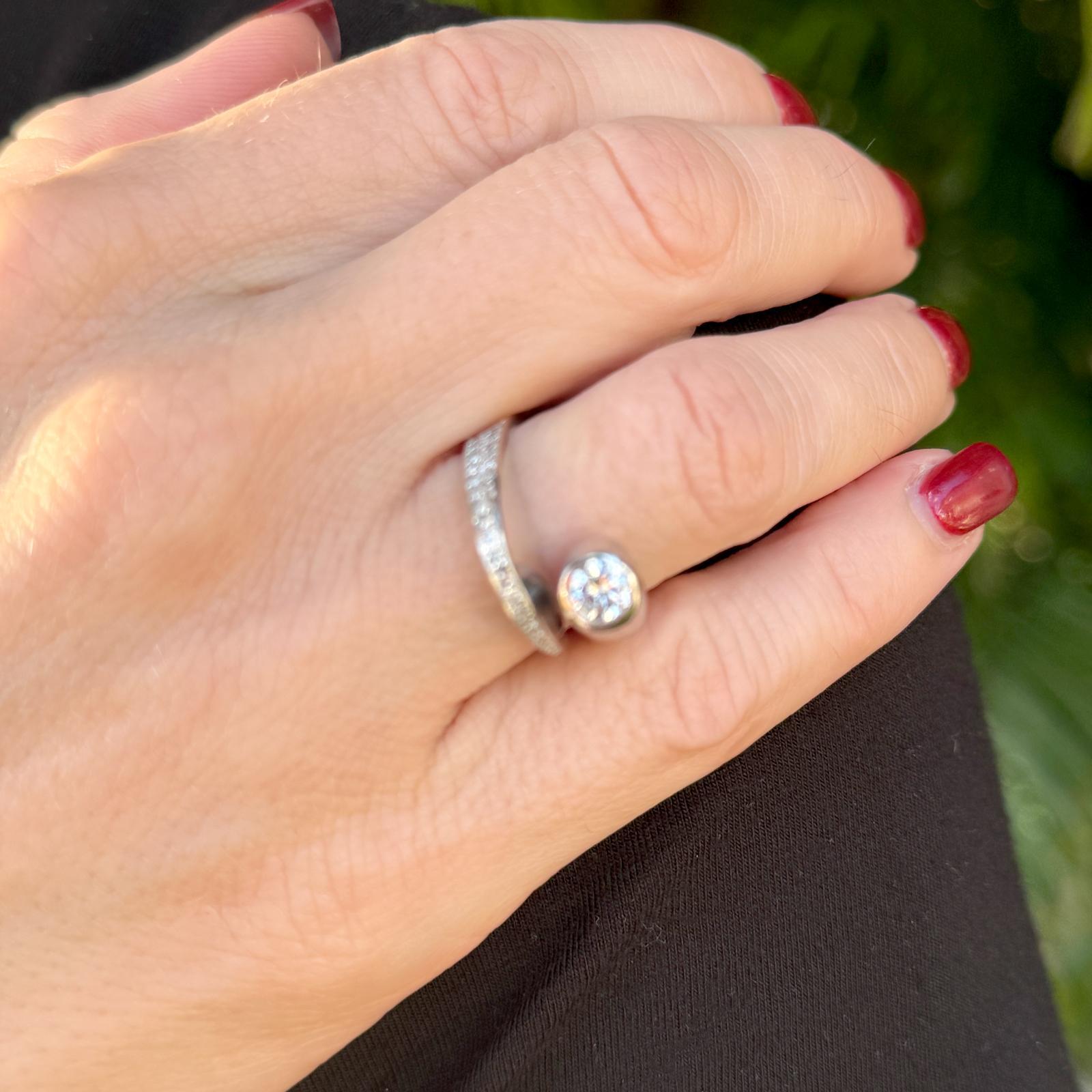 This Modern Diamond Crossover Ring features a stunning design crafted in 14 karat white gold, showcasing a brilliant arrangement of diamonds. At its center, an approximately 0.49-carat diamond takes focus, complemented by 26 side stones with a total