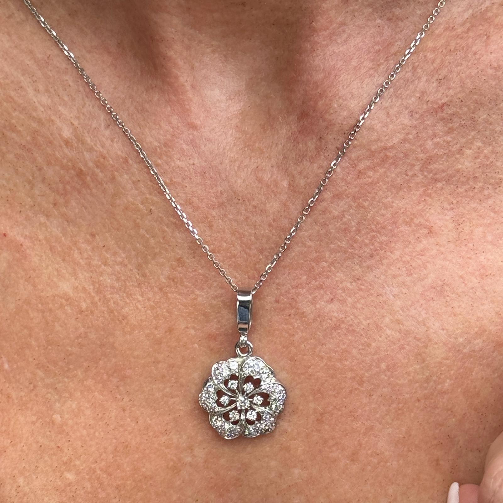 Beautiful modern diamond floral pendant necklace crafted in platinum with a 14 karat white gold baile and chain. The pendant features round brilliant cut diamonds weighing approximately 1.00 carat total weight and graded H-I color and SI clarity.