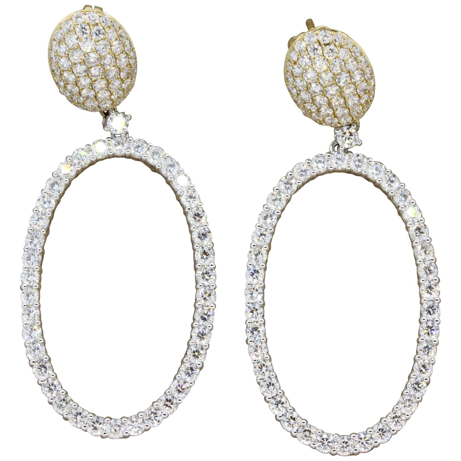 A modern take on the classic hoop earrings, this pair is a unique drop pair of hoops. It is studded with 6.22 carats of VS quality round cut diamonds. Set in white and yellow gold, these marvelous pair of earrings deserve a marvelous owner.