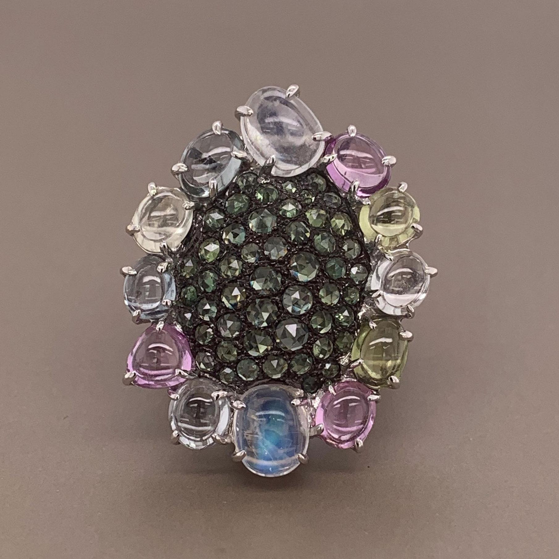 A fun multi-color cocktail ring featuring sapphires, diamonds and moonstones. There are 11.82 carats of sapphire and moonstone cut as large cabochons and smaller rose cuts in the center of the ring. They are complemented by 0.38 carats of round cut