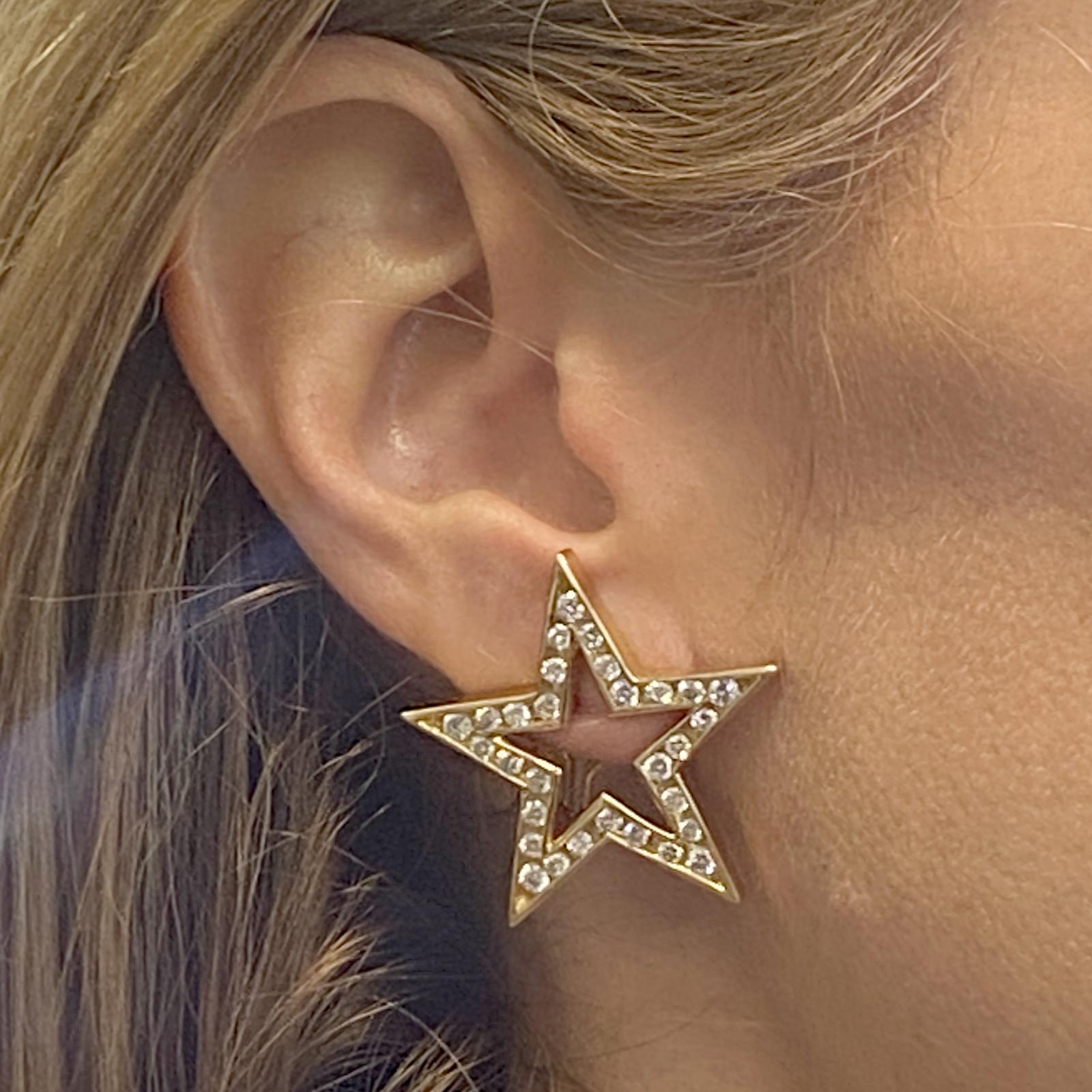 Stylish open star diamond earrings fashioned in 14 karat yellow gold. The earrings feature 56 round brilliant cut diamonds weighing approximately 2.50 carat total weight and graded G color and VS2-SI1 clarity. The stars measure 1.25 x 1.25 inches