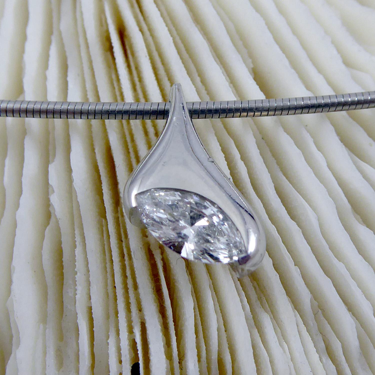 A striking contemporary diamond and platinum necklace featuring a 0.30ct marquise shaped diamond, G colour, VS clarity set into a partial rub over set platinum mount.  The pendant suspends from a platinum cable wire which fastens with a crocodile