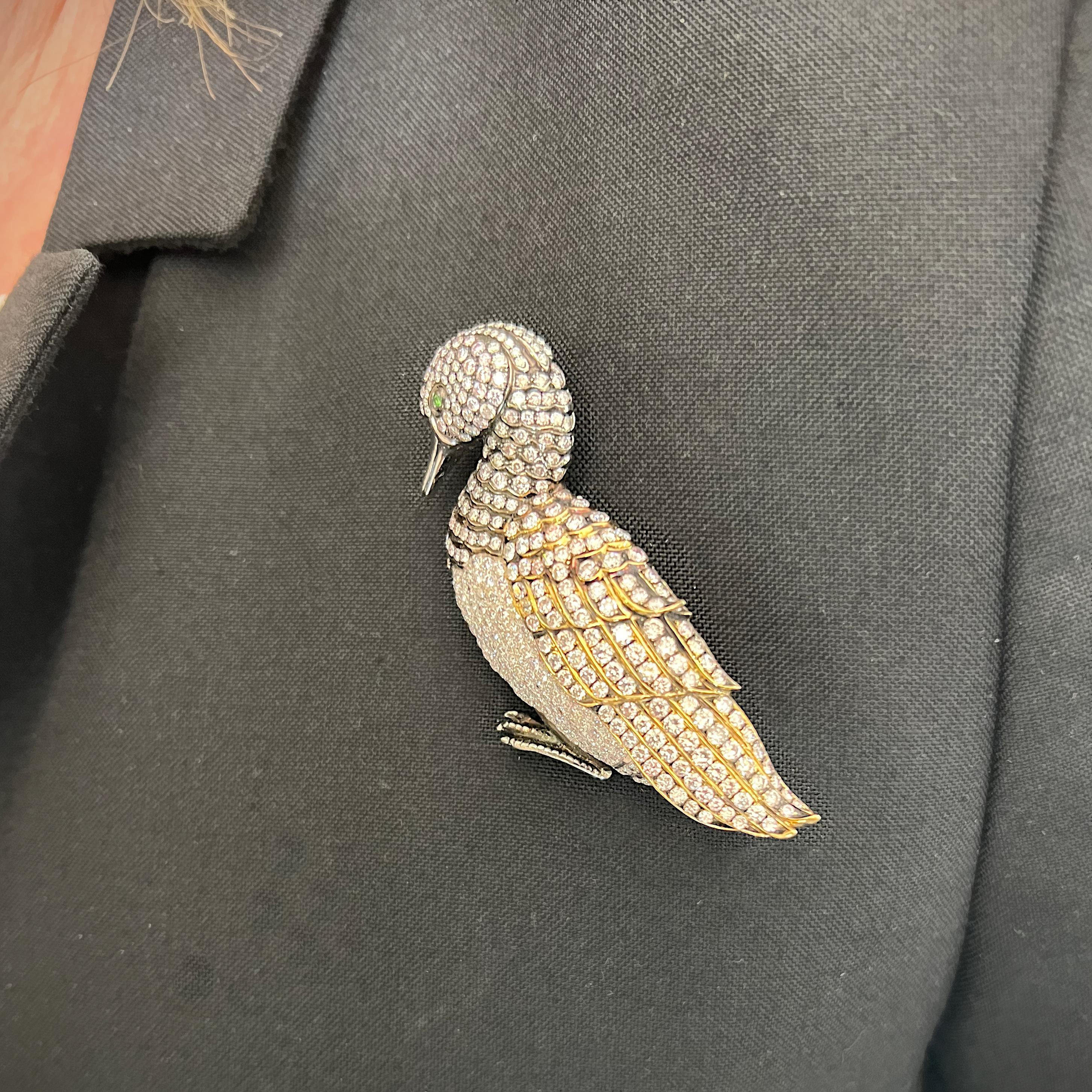 A diamond set duck brooch, with round brilliant-cut diamonds, with pinky-brown tint to represent feathers, pavé set in platinum, with an 18ct yellow gold wing and oxidised metal detail to the head, neck and wing, and green garnet eye. The estimated