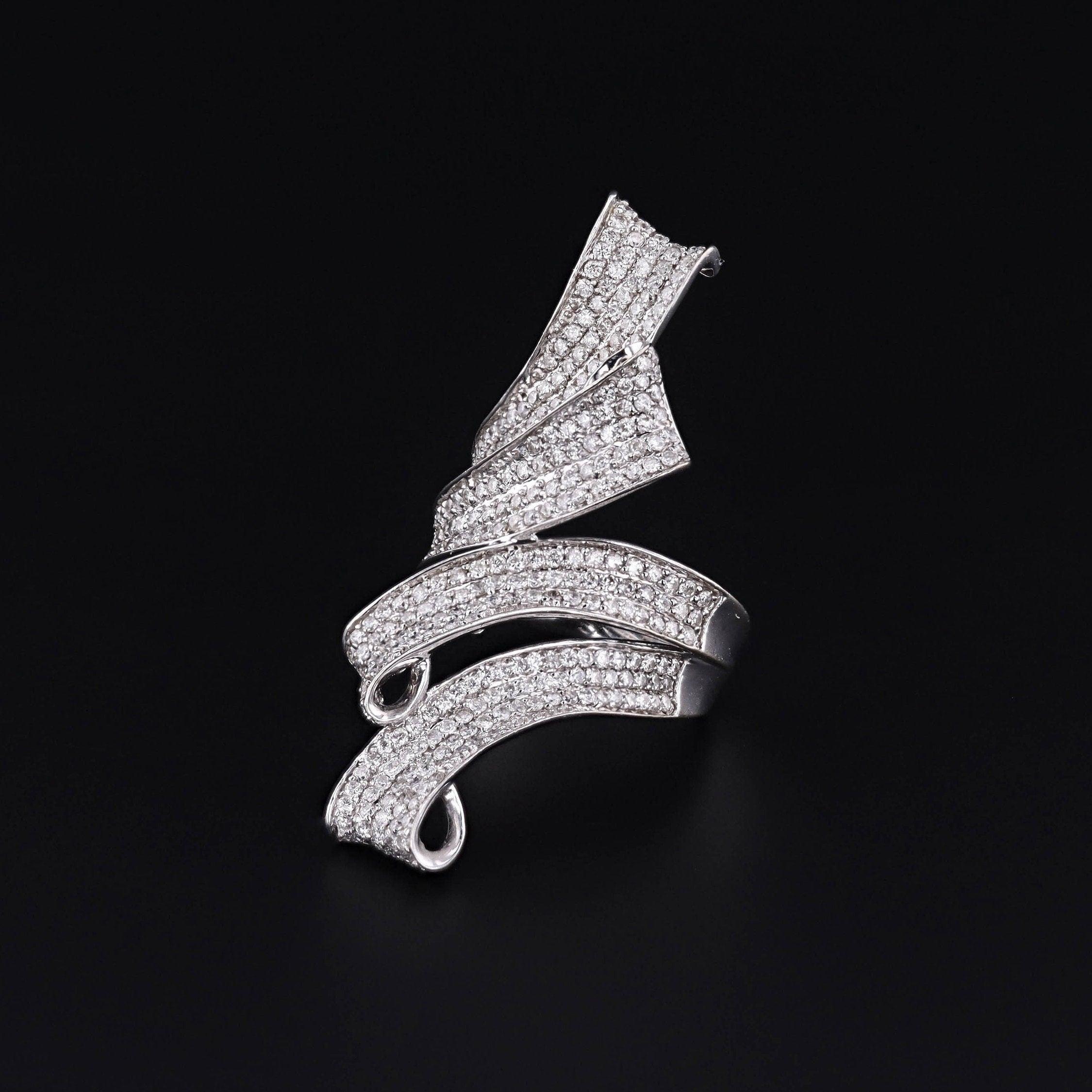 Questo anello (circa 2000-2010) presenta nastri di diamanti scintillanti (con un peso complessivo di 1,50 carati) incastonati in oro bianco 14k.

Il sostanzioso anello misura 1,8 pollici da nord a sud ed è in ottime condizioni. L'anello è una taglia