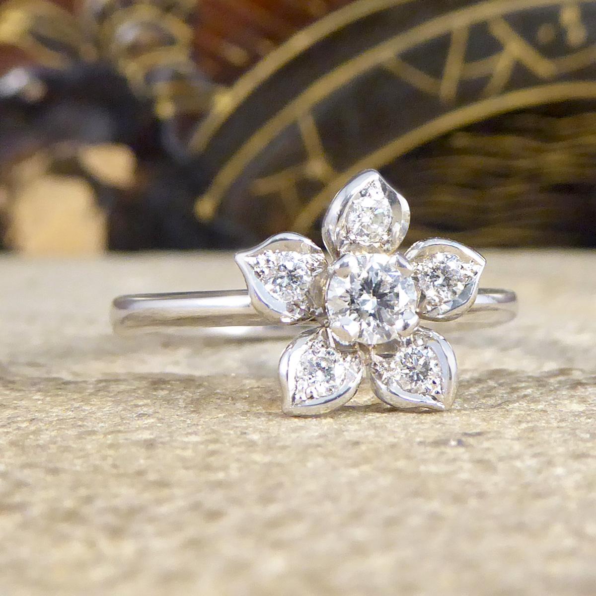 Such a lovely and dainty design. This ring has been carefully crafted with great detail and beautifully shaped petals each adorned with a single Diamond clustering a larger centre Diamond. Crafted fully in 18ct White Gold, this ring would make a