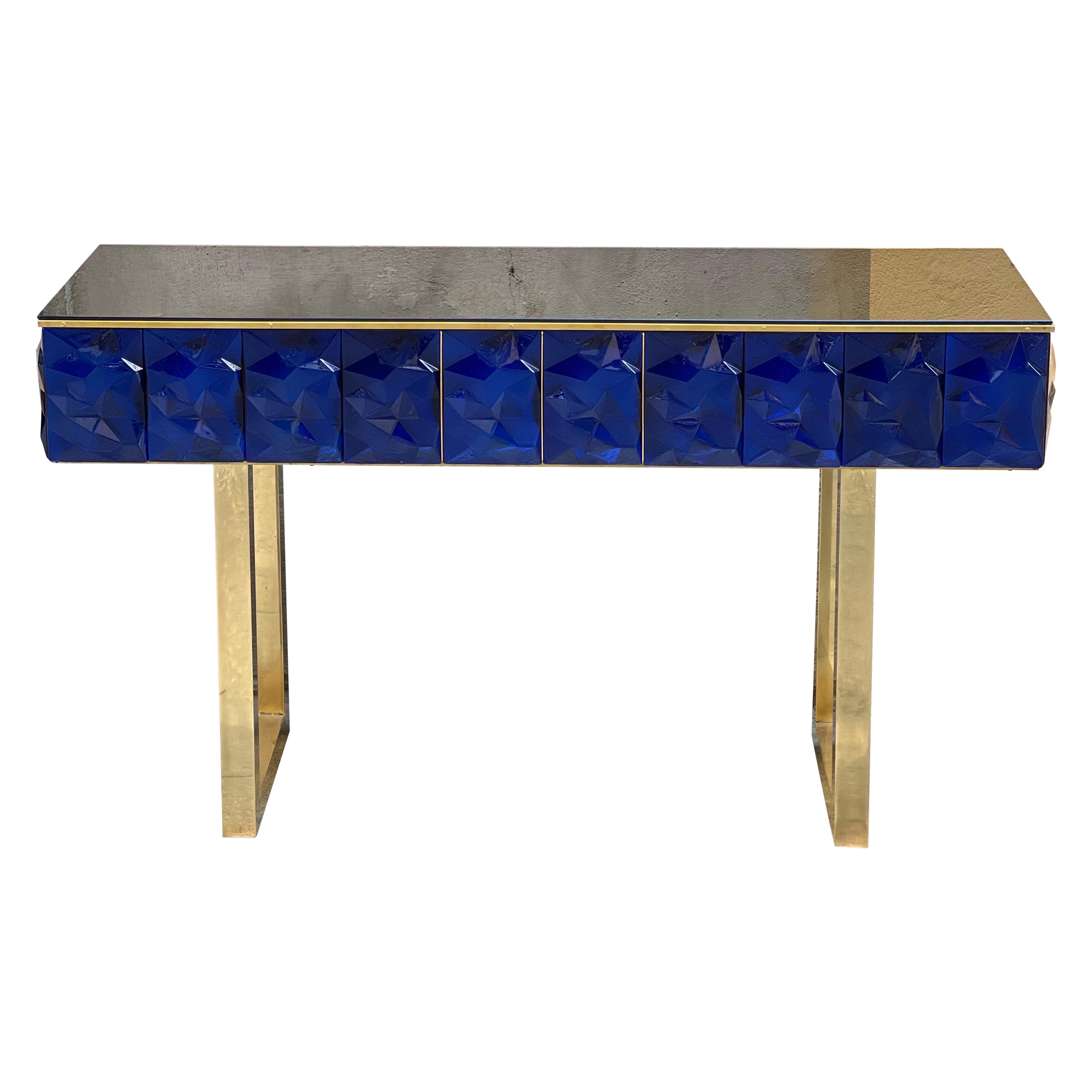 Consola contemporánea de cristal de Murano azul tallado en forma de diamante con tapa de cristal opalino negro y estructura y herrajes de latón.
El cristal de Murano azul tiene un efecto diamante con forma facetada, la luz que lo atraviesa crea un