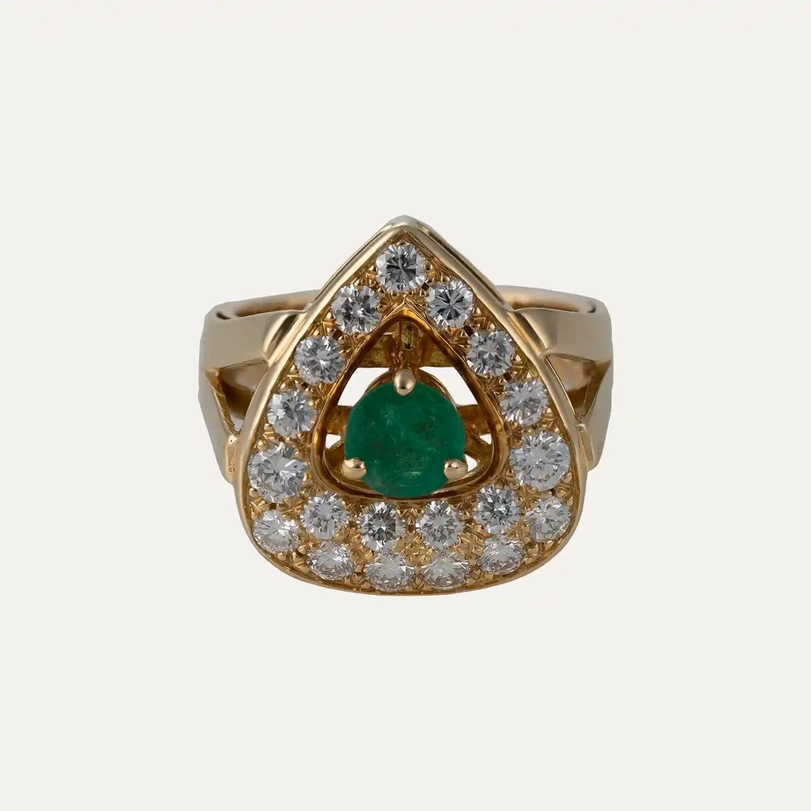 
Bague en or jaune 18kt - 750‰, de forme triangulaire arrondie,  avec 1 émeraude de taille ronde au centre totalisant environ 2,61ct et entourée de 19 diamants de taille brillant.