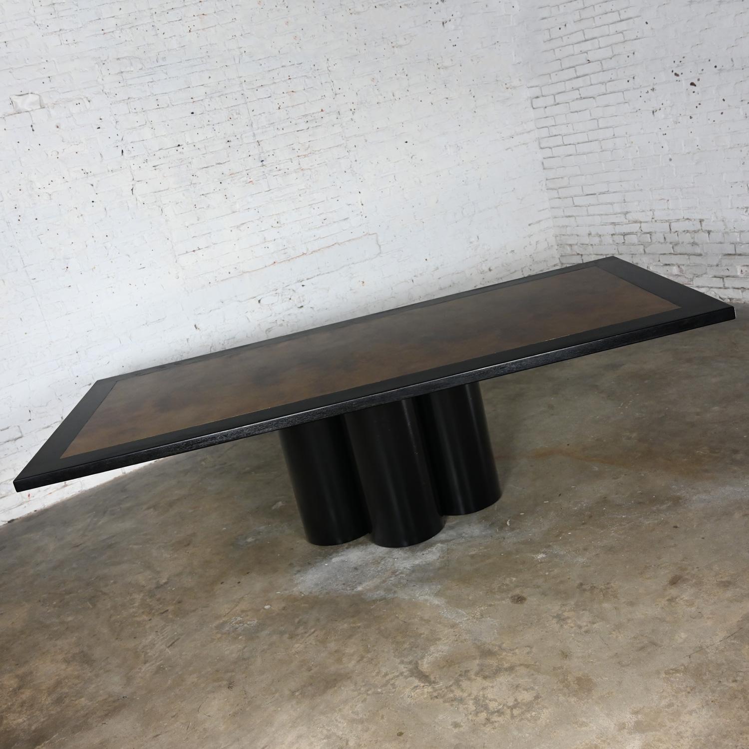 Fabulous modern dining table with a four-cylinder black painted metal pedestal base, dyed black oak tabletop frame, and aged brass center insert in the style of Bernhard Rhone for Mastercraft.  Beautiful condition, keeping in mind that this is