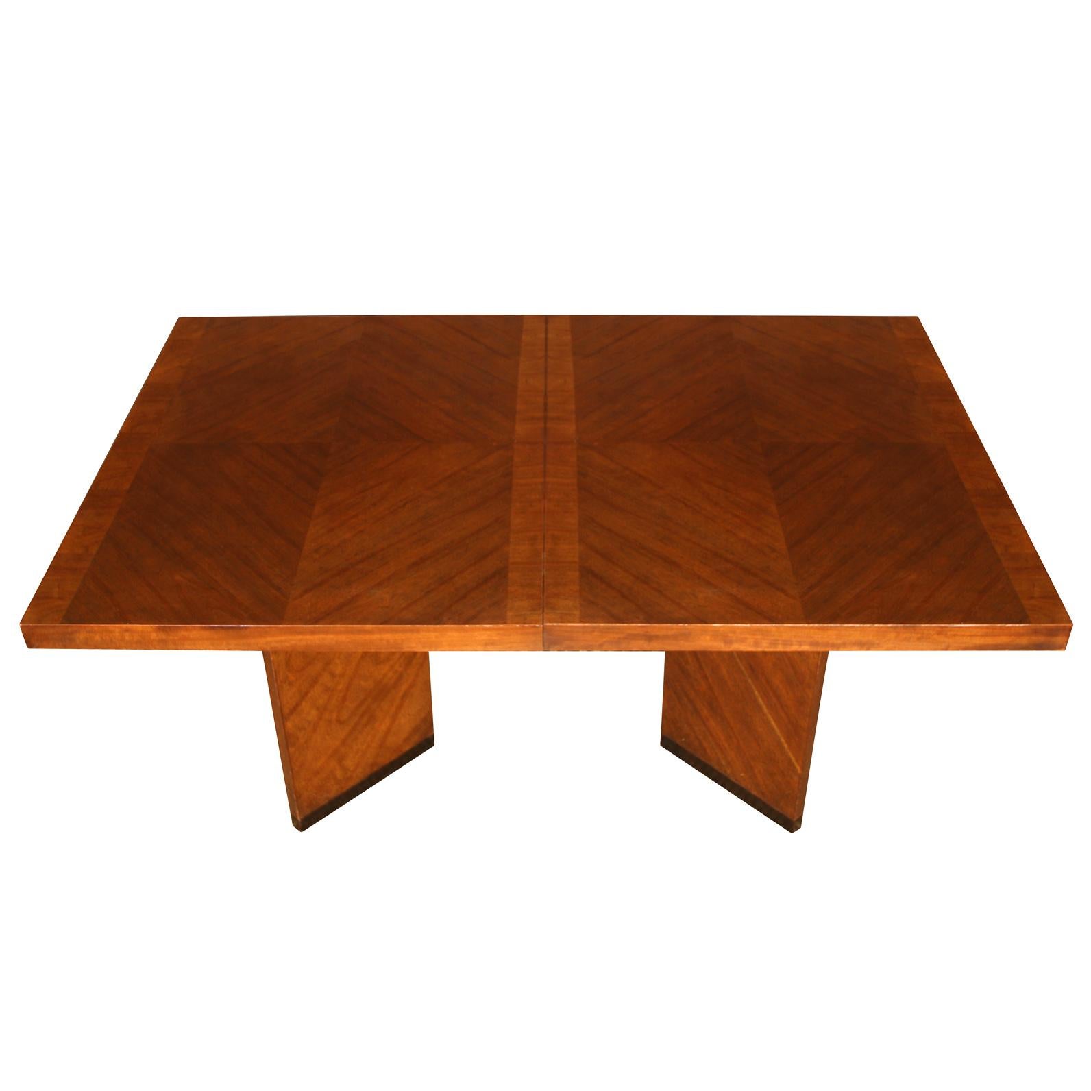 Vintage rectangular dining table in modern style with a bordered chevron inlay top, double angular pedestal base and two leaves in medium tone wood. Each leaf measures 18