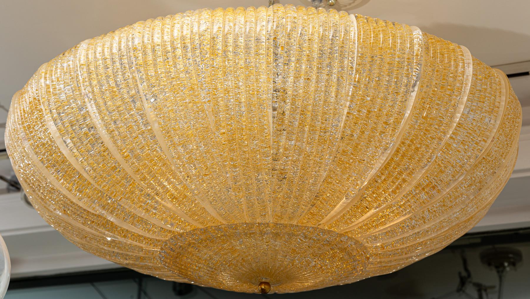 26 curved rib textured blown glass sleeves compose this sleek round near flush mount ceiling fixture finishing with a circular ribbed plate and nickel polished finial.   Warm light amber color blown into clear glass.

Electrified to code with 6