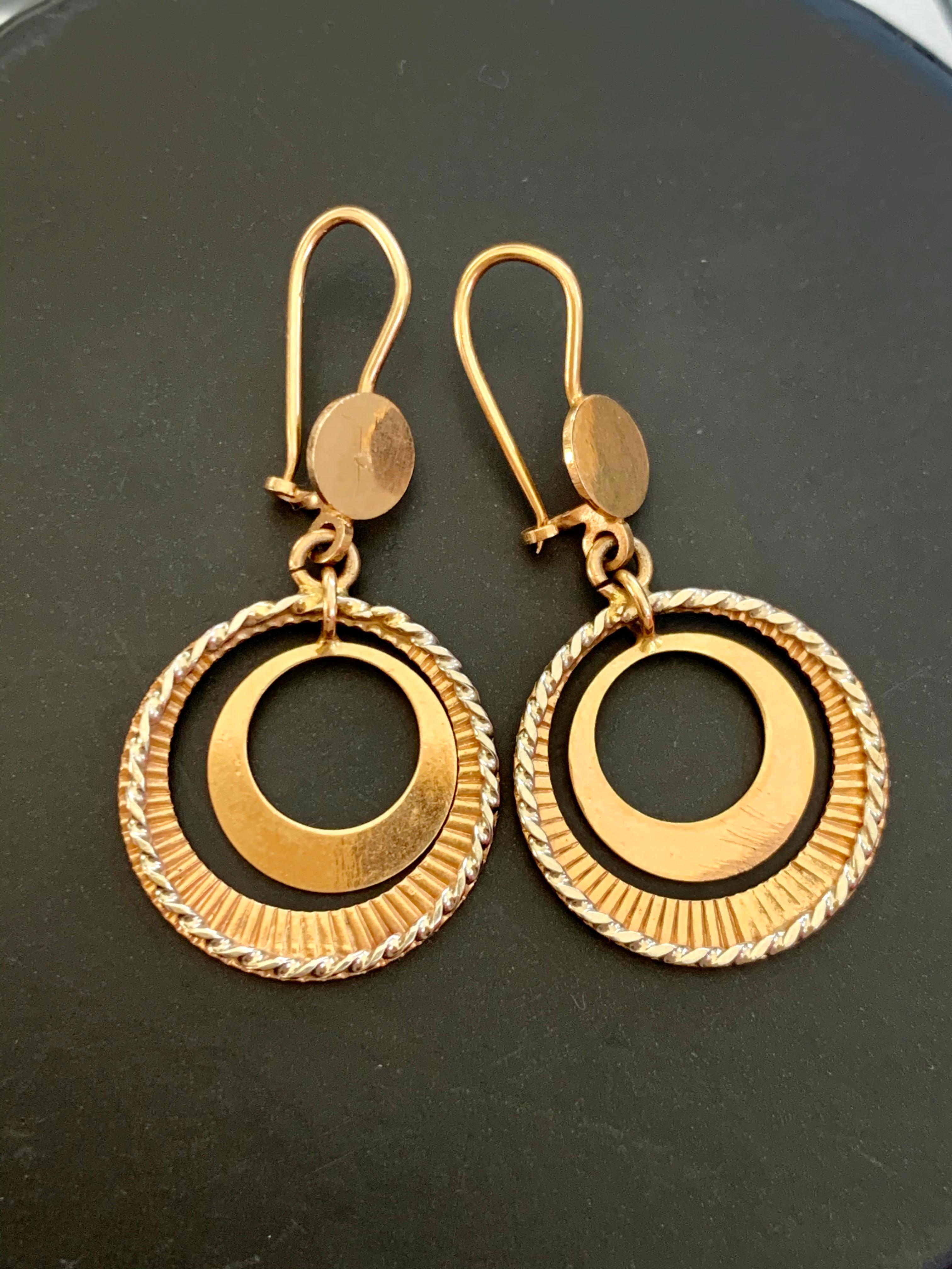 These fun double hoop earrings feature several different textures and finishes for a unique twist on traditional hoop earrings.  The smaller inside hoop has a shiny Gold finish which reflects light and colors from the wearer's surroundings.  The