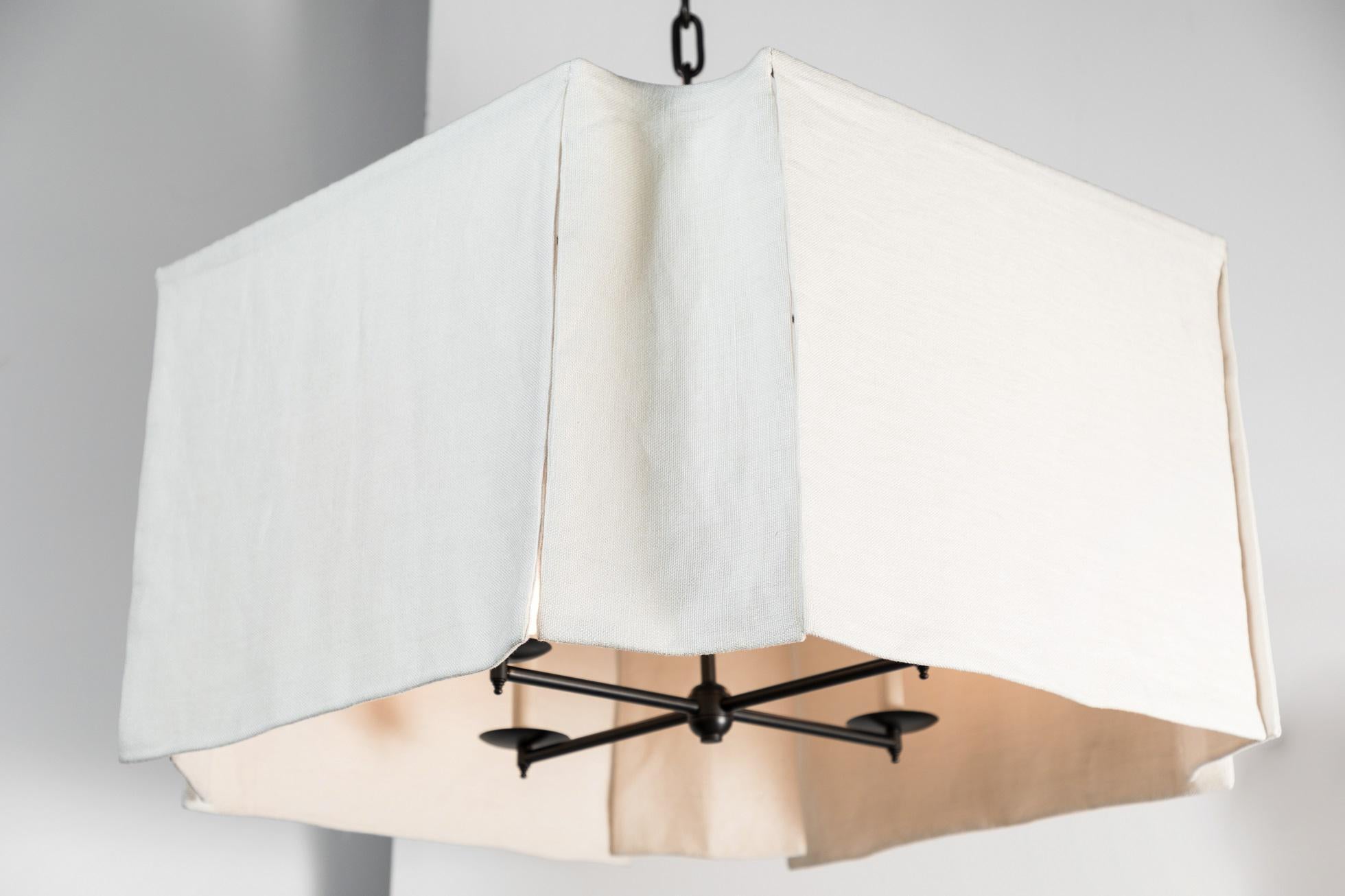 Modern draped chandelier by Paul Marra, shown in white linen fabric. Hand-sewn. Casual elegance. This can also be ordered in COM (approximately 3 yards). Oil rubbed bronze finished (4-light) cluster, canopy and chain. Total drop of 5' as shown. 60w