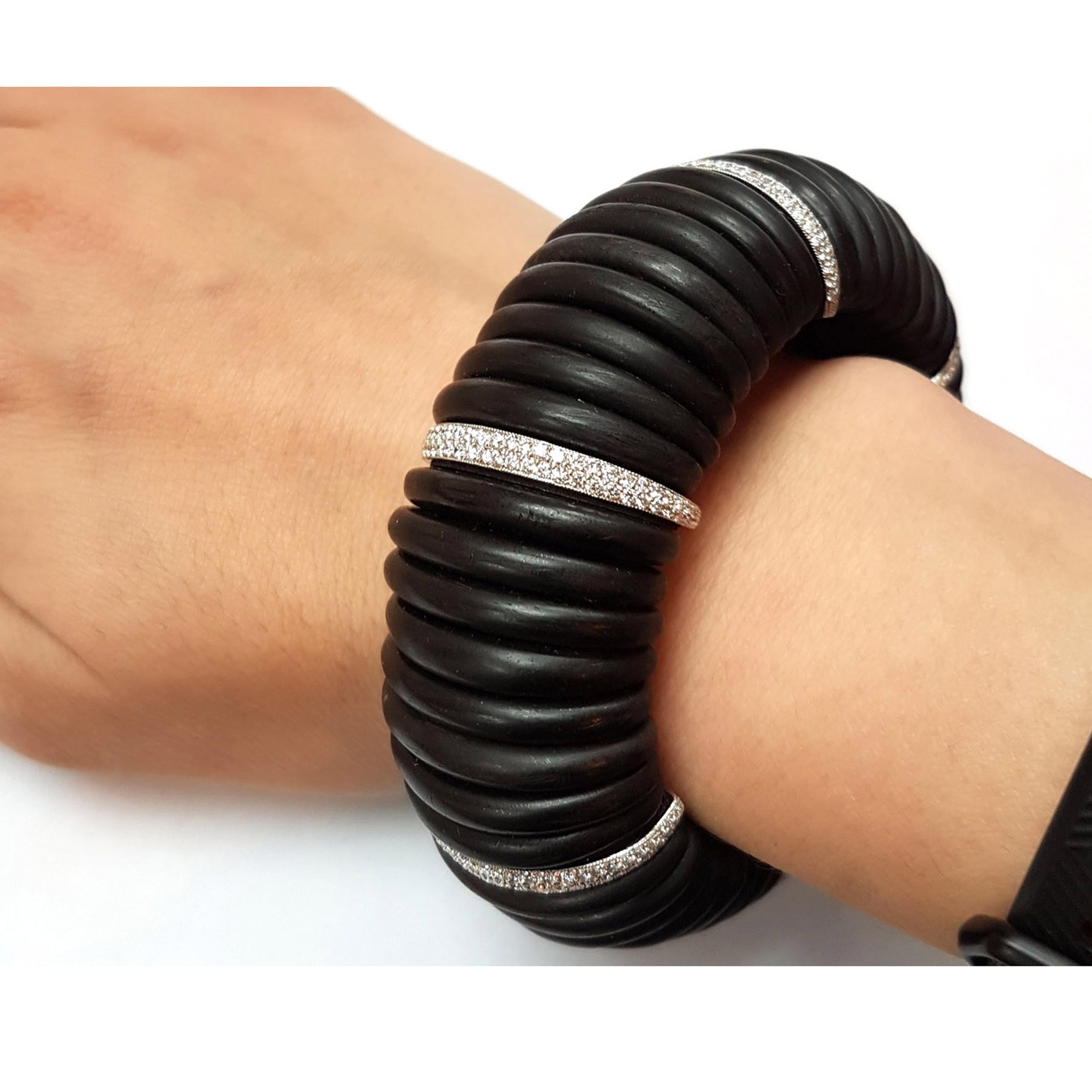 An ebony and diamond cuff bracelet, designed as a repeating pattern of eight, ebony segments, spaced by a diamond link, which is pavé set with two rows of graduated, round brilliant-cut diamonds, in platinum settings, weighing an estimated total of