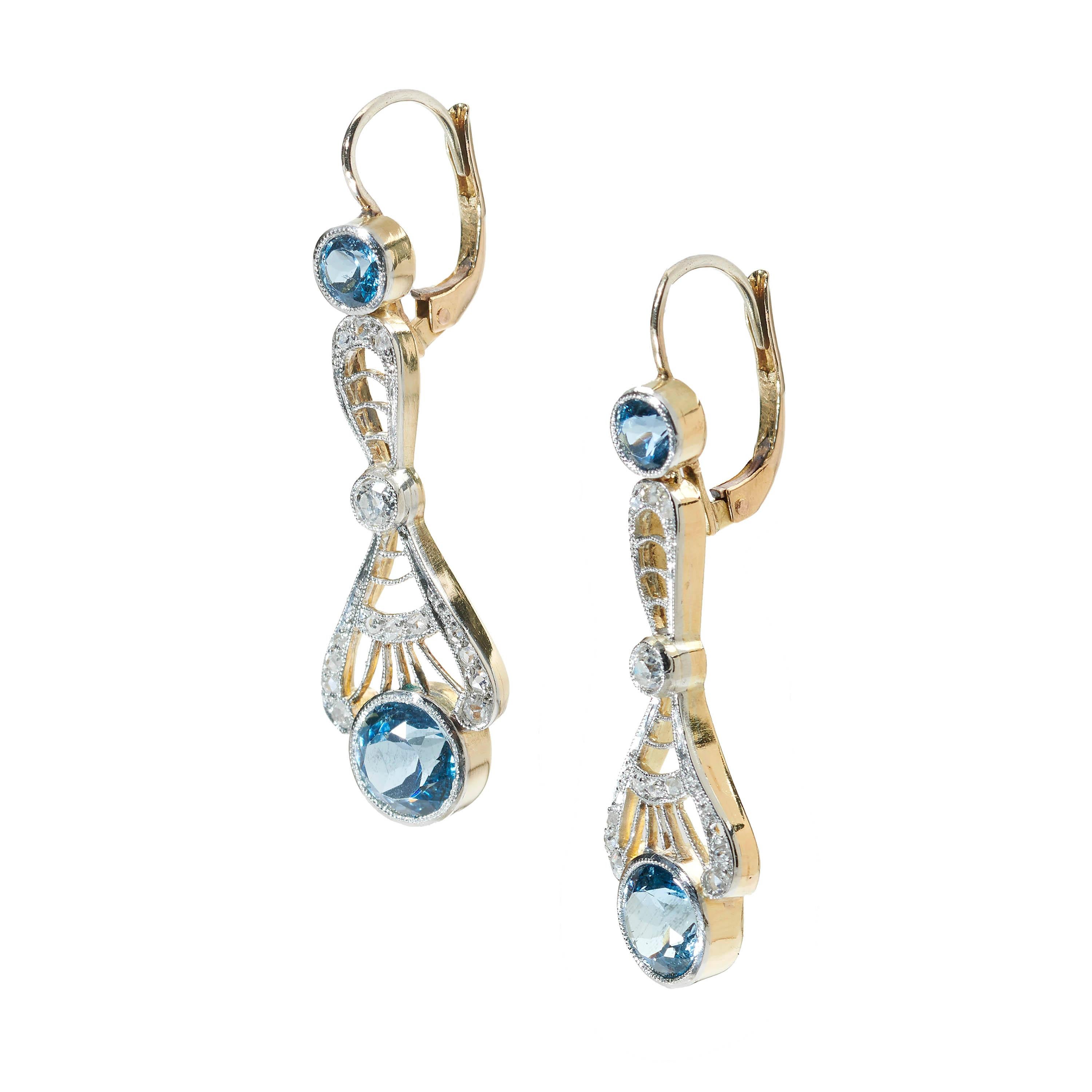 A pair of Edwardian style aquamarine and diamond drop earrings, set with round faceted aquamarines and rose-cut diamonds, weighing an estimated 0.25ct, with rub over and grain settings and millegrain edges, mounted in gold with silver settings.
