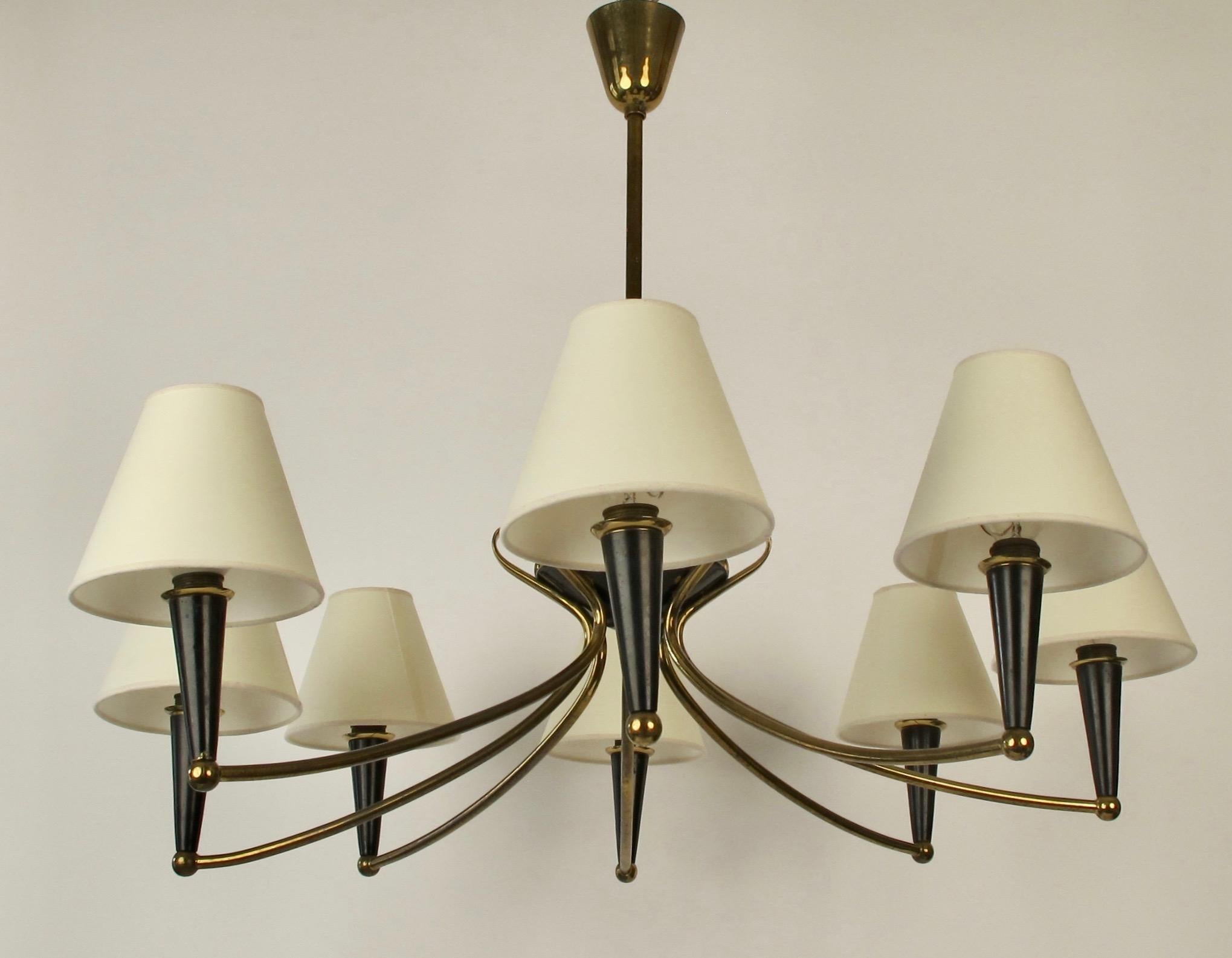 Modern Austrian chandilier with eight arms from the 1950's. The composition of the lamp
is made up of brass and blackened metal elements, The the brass arms swing upwards and form a crown
in the middle of the lamp.

The shades have been renewed,
