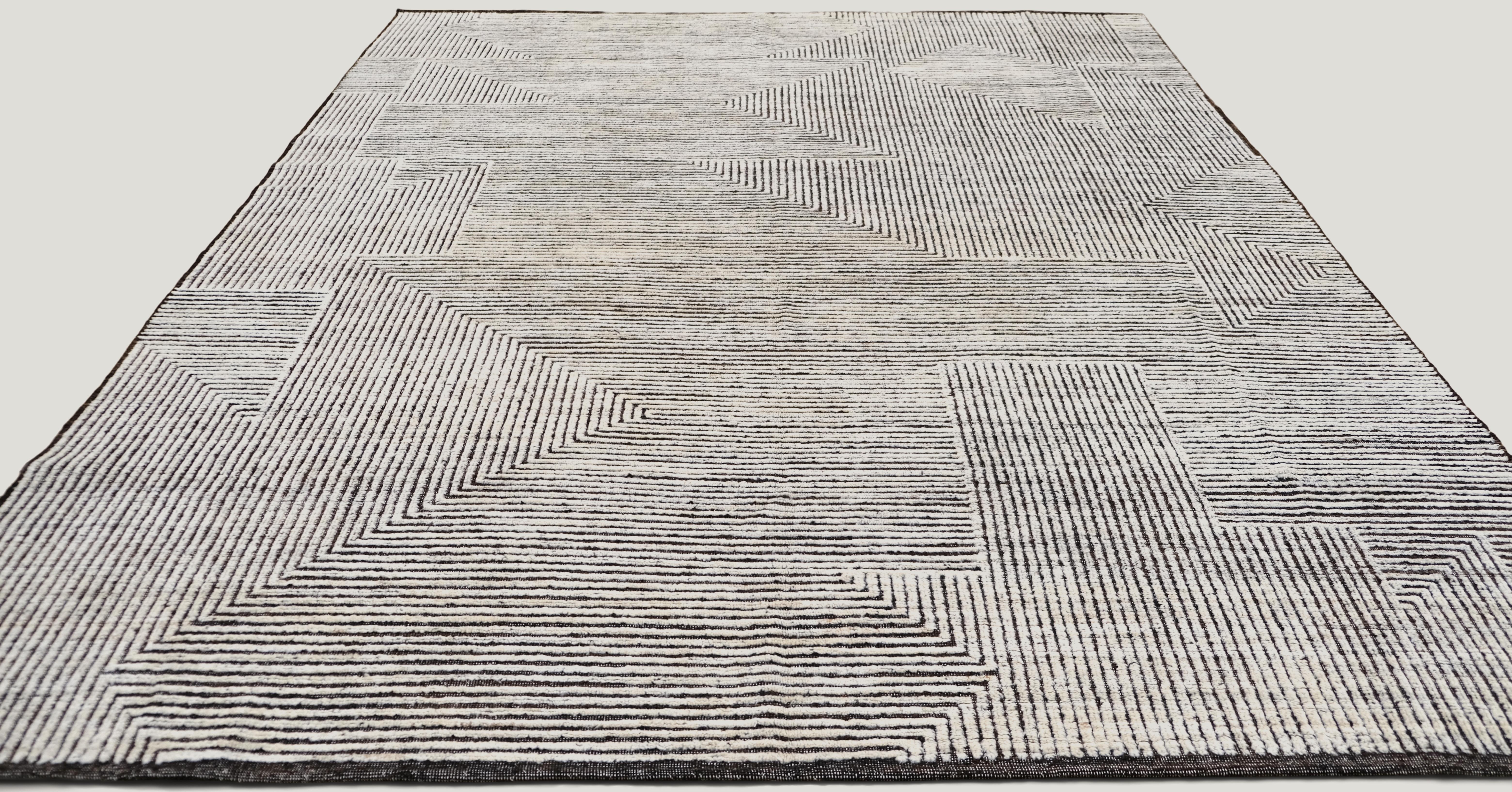 Dieser handgeknüpfte Wollteppich mit seinem atemberaubenden geometrischen Muster in Schwarz/Braun und Elfenbein wertet Ihre Inneneinrichtung auf. Das verschlungene Muster aus durchgehenden Linien schafft eine fesselnde moderne Ästhetik, die